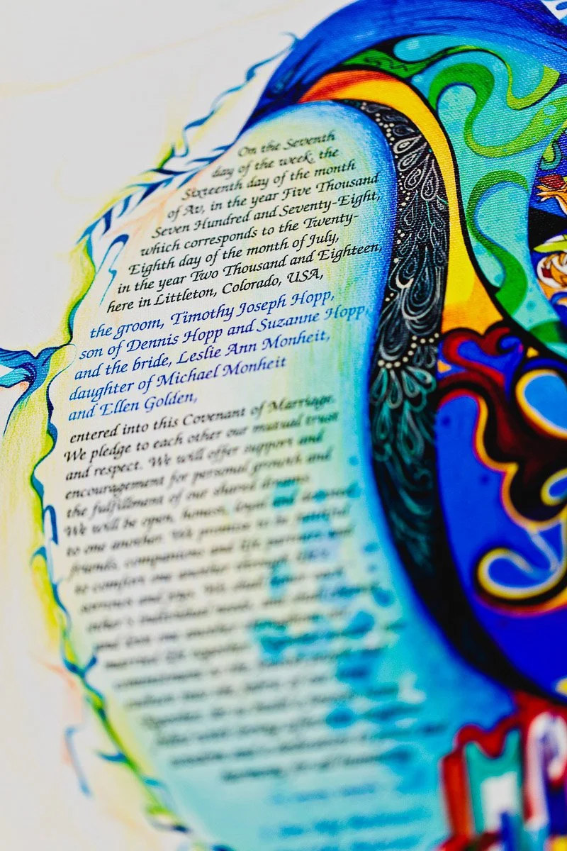 Close-up of a colorful artistic text document featuring intricate blue and yellow designs. The text is about a marriage covenant, conveying a joyful, celebratory tone.
