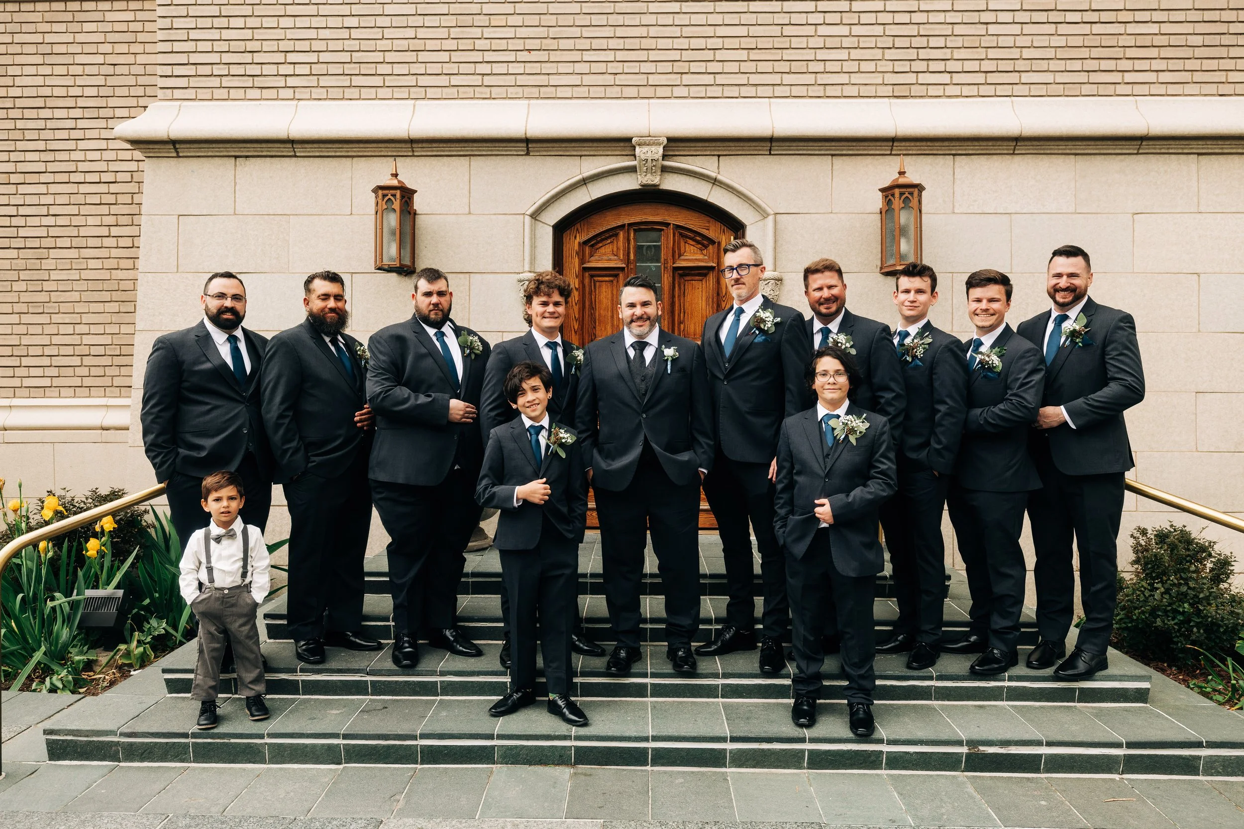 Groomsmen, ushers and ring bearer gather outside on the street before a Holy Ghost catholic church wedding in Denver, Colorado