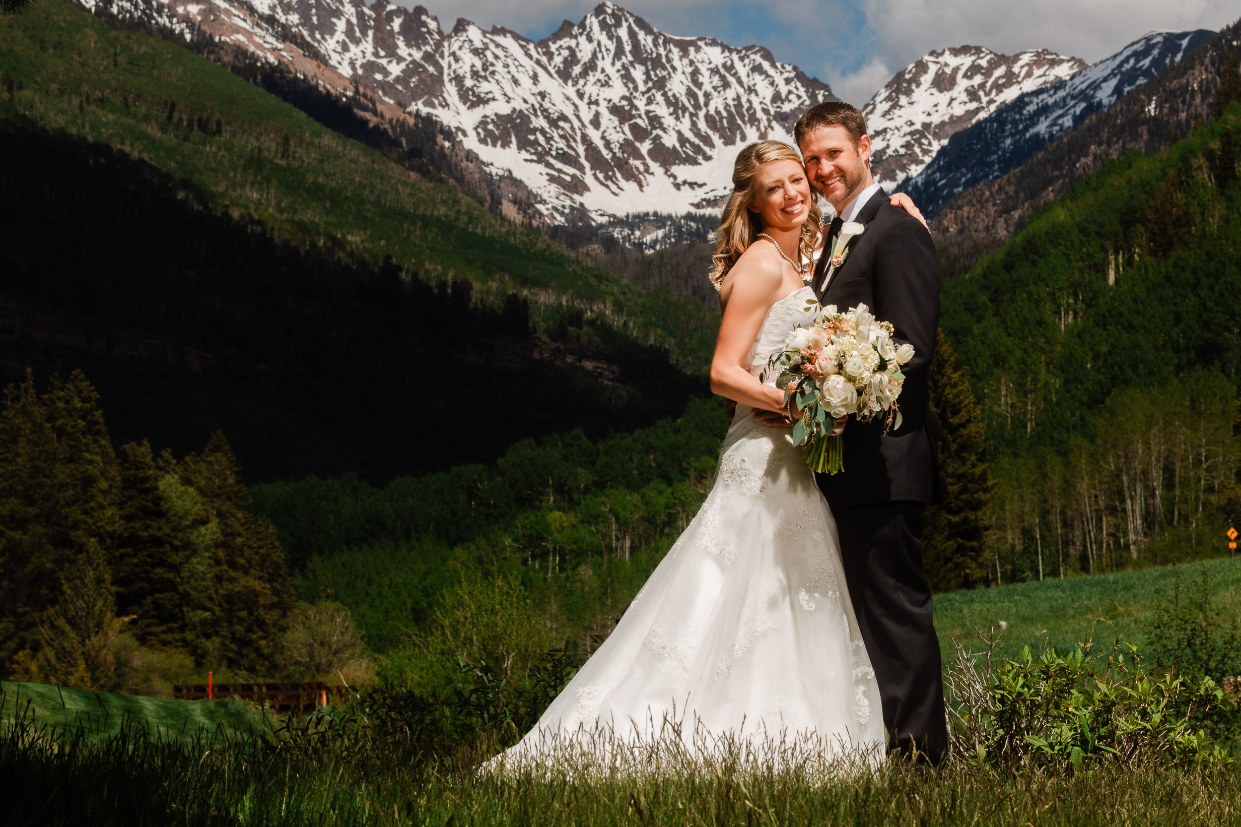 Bride and groom embrace for a couples portrait in front of the Gore Mountain Range during a Dovovan Pavilion wedding in Vail, Colorado