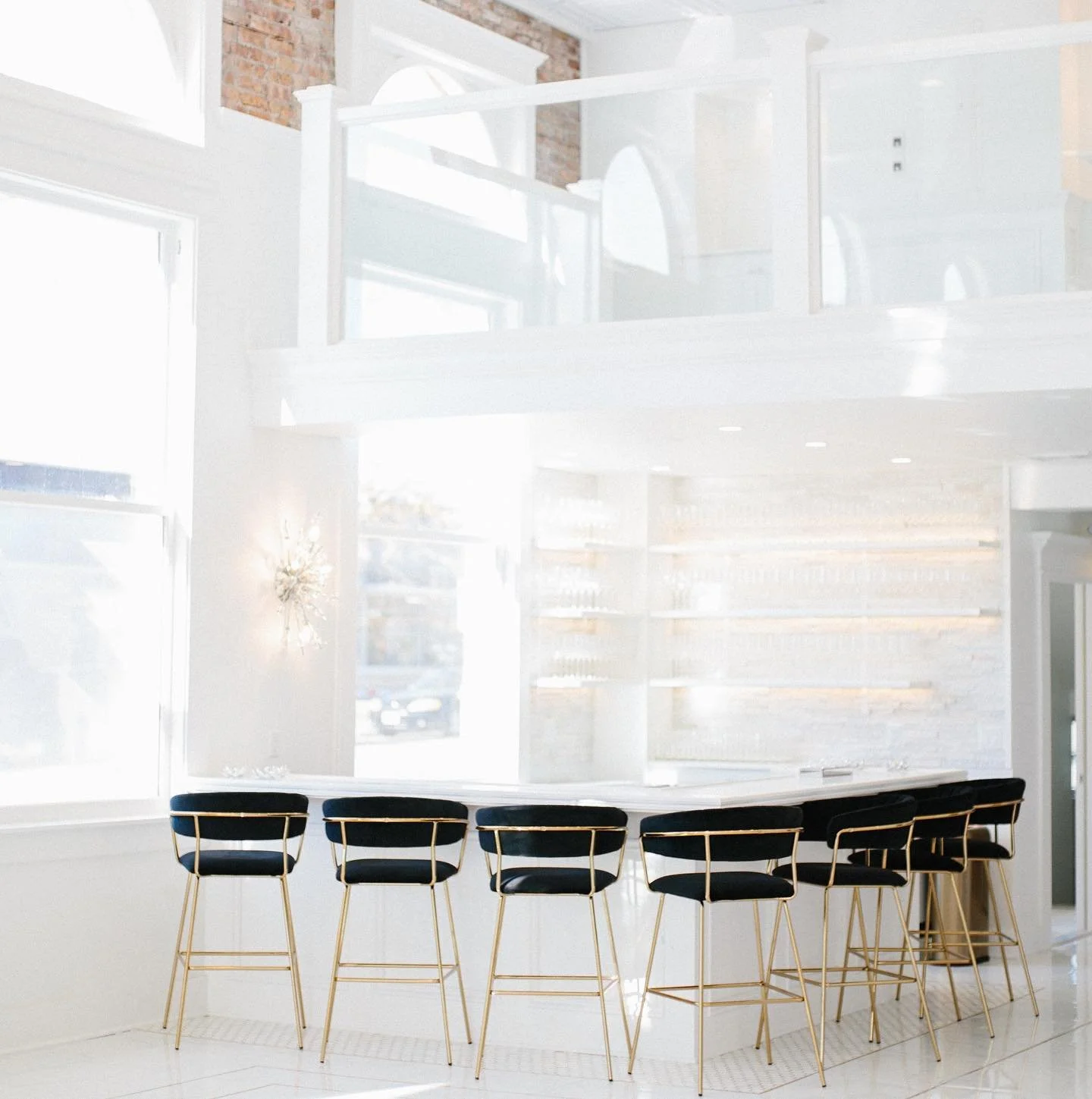 Modern bar area inside The Treasury wedding venue in Delavan Wisconsin with white interior, gold bar stools, and natural light.