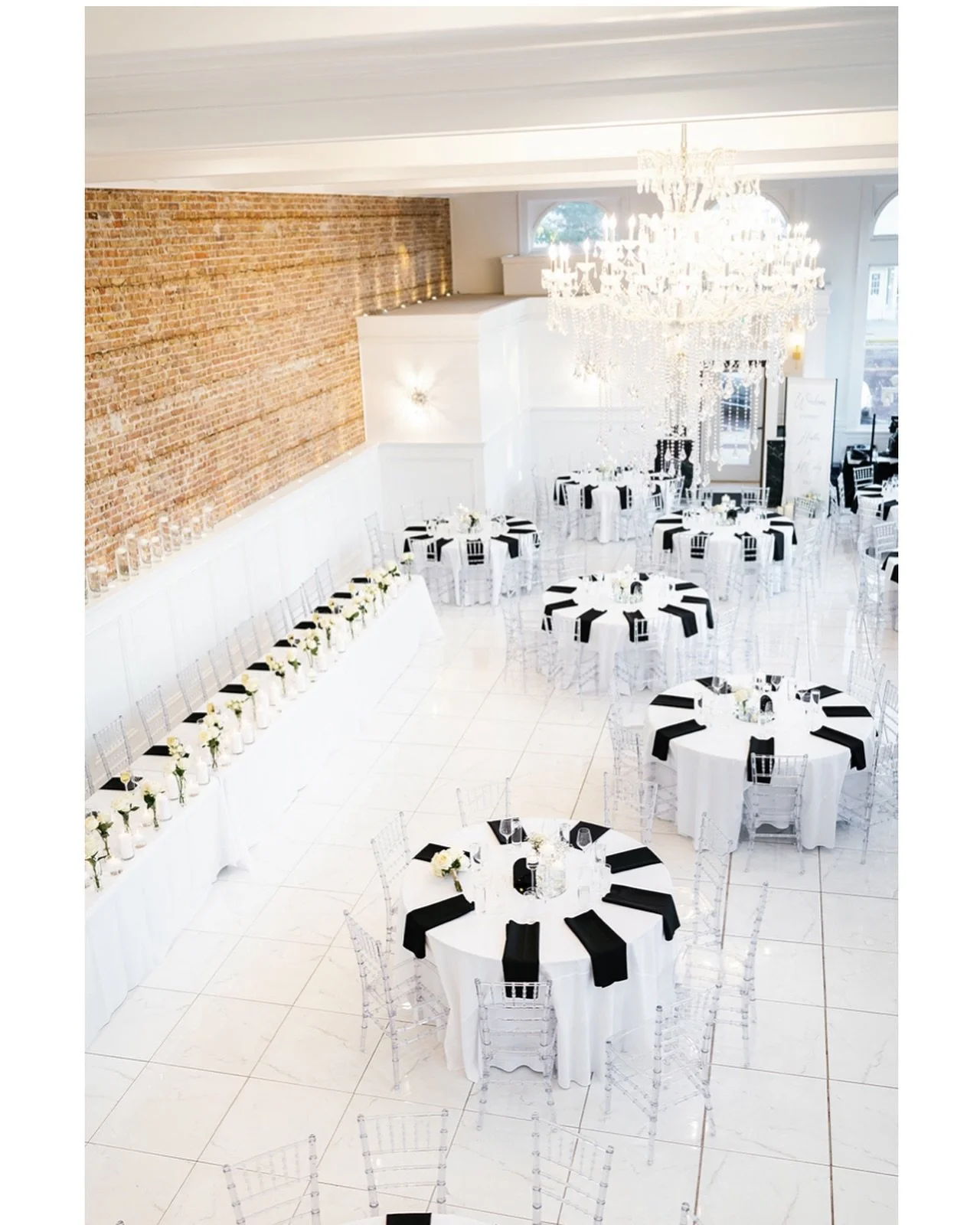 Wedding reception setup at The Treasury venue in Delavan Wisconsin featuring chandeliers, exposed brick walls, and elegant table layouts.