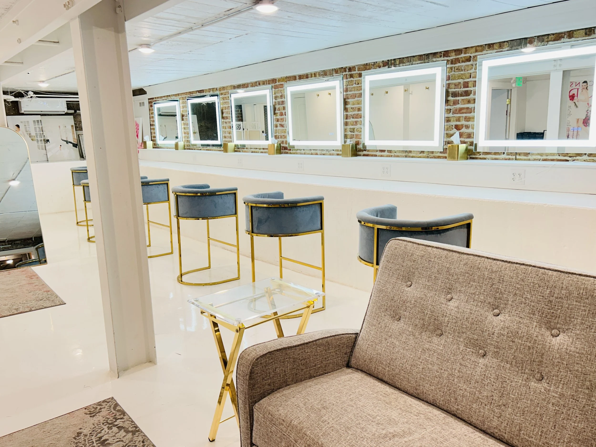 Bridal getting ready suite at The Treasury wedding venue in Delavan Wisconsin featuring lighted mirrors, exposed brick wall, and modern seating.