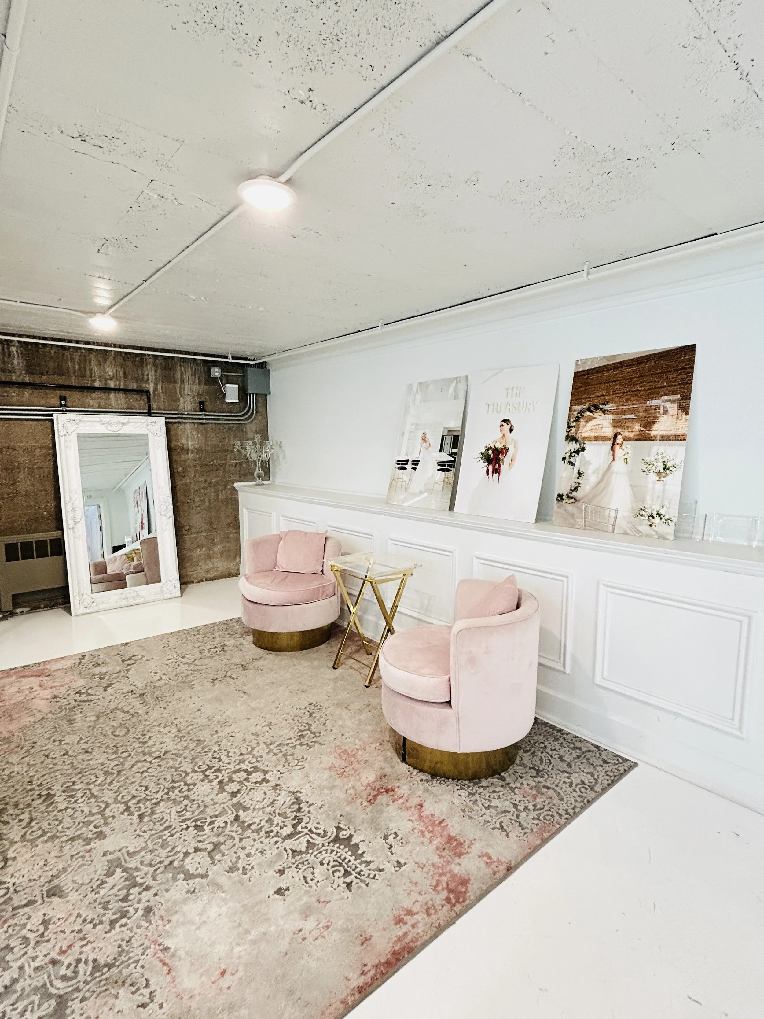 Stylish lounge and photo area inside The Treasury wedding venue in Delavan Wisconsin with pink chairs, vintage mirror, and modern decor.