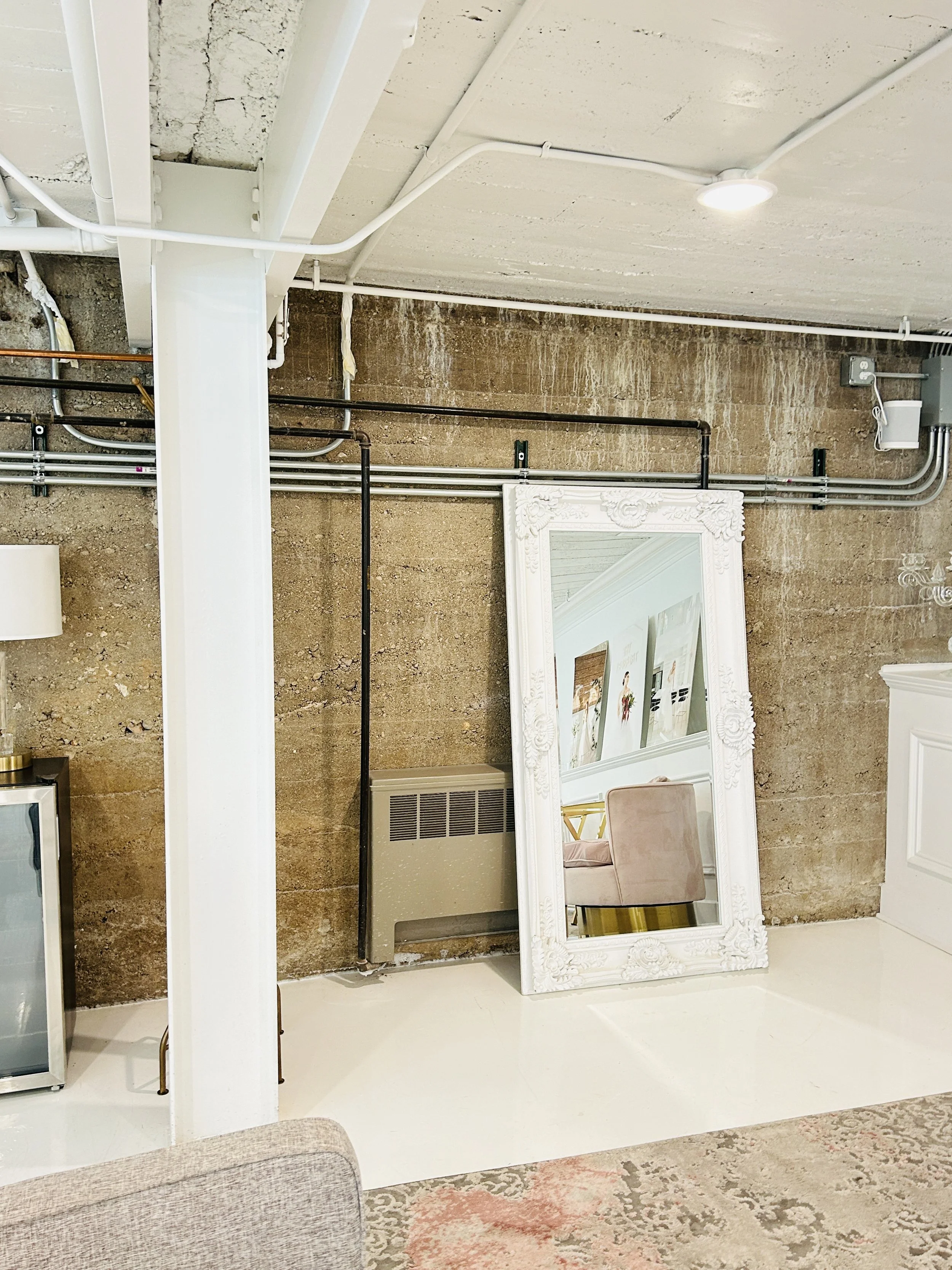 Vintage mirror photo area inside The Treasury wedding venue in Delavan Wisconsin featuring exposed stone wall and elegant lounge decor.