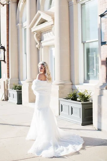 Bride standing outside The Treasury wedding venue in Delavan Wisconsin in front of the historic building columns.