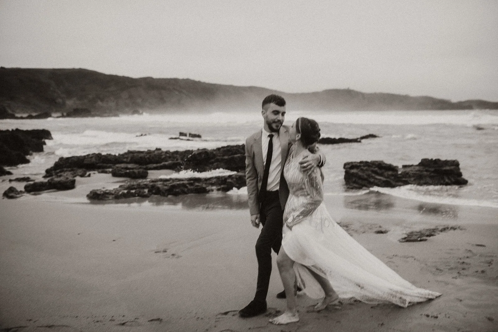 Pareja caminando por la playa durante una sesión de fotos de boda natural en Asturias