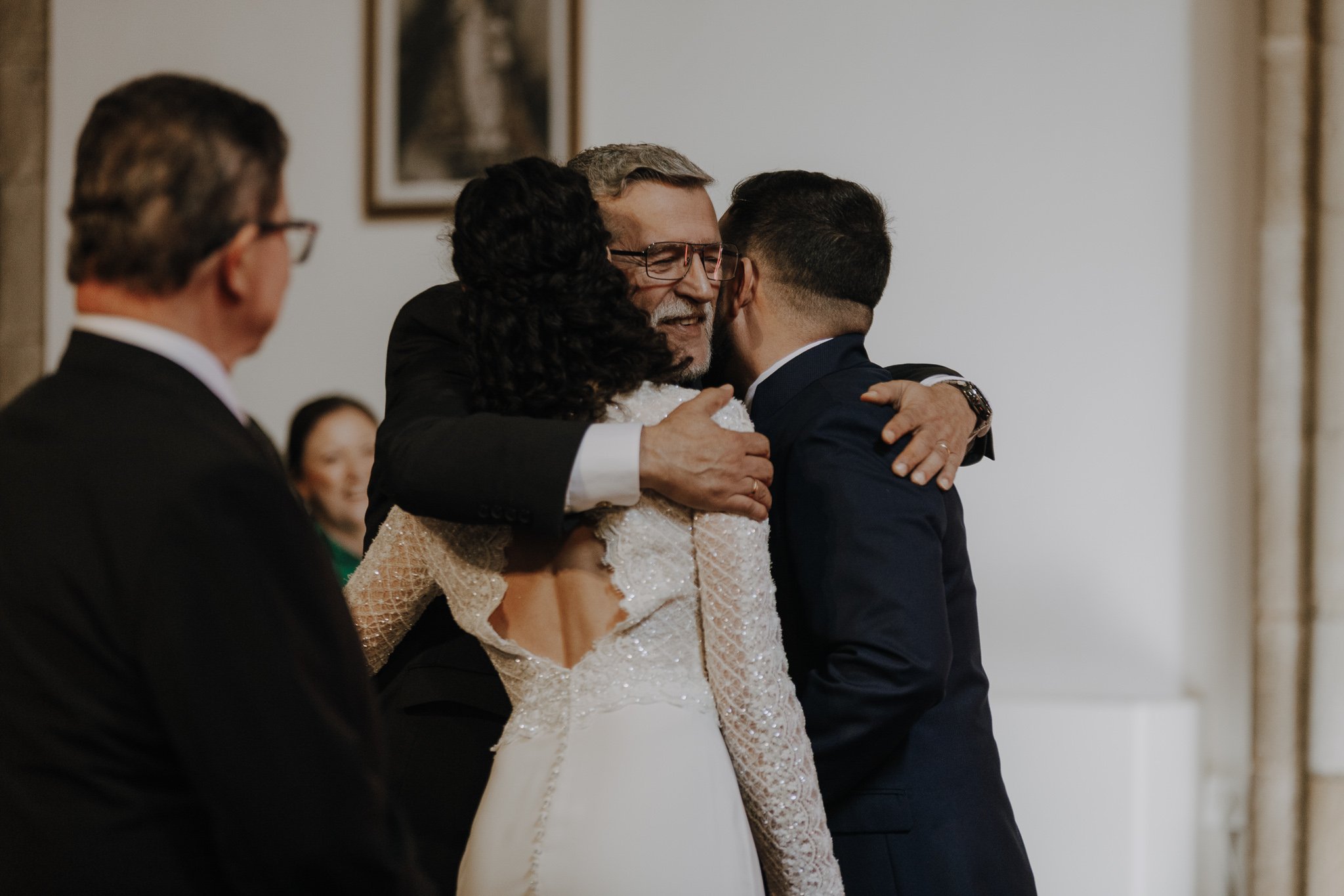 Pareja abrazando a un familiar en la ceremonia de la boda
