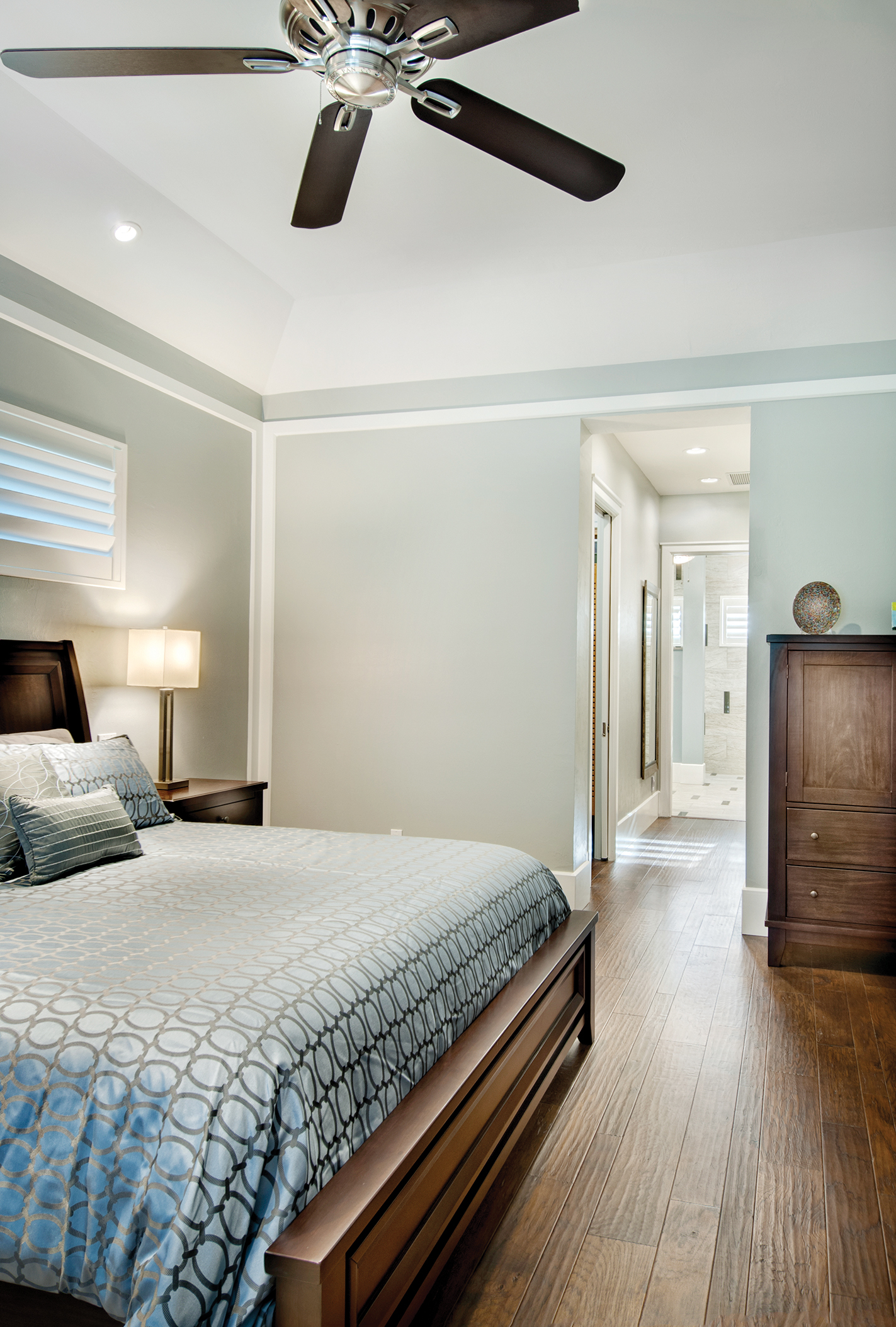  The master suite is tranquil with shades of soft blue. “We wanted to keep this room simple and comfortable,” says Sater. Through the hall, the master bath sports more of the beautifully stained woods found throughout the home. 