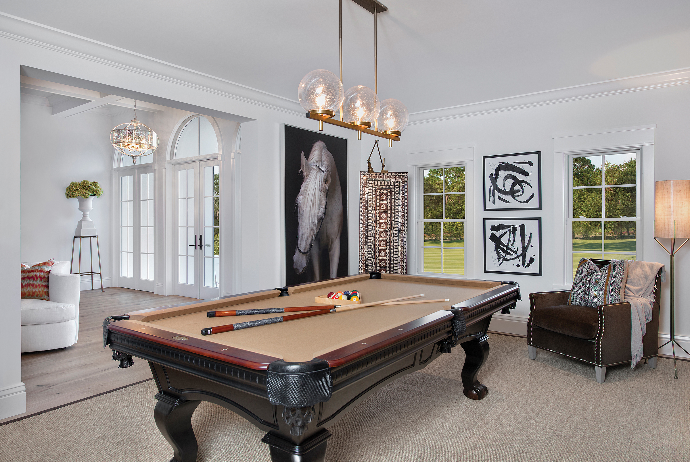  “I wanted to create a distinctly masculine area in this house and I think this room turned out to be a wonderful space with a global feel,” says Williams of the billiards room. Roman shades, the animal skin rug, and antler accents add exotic touches