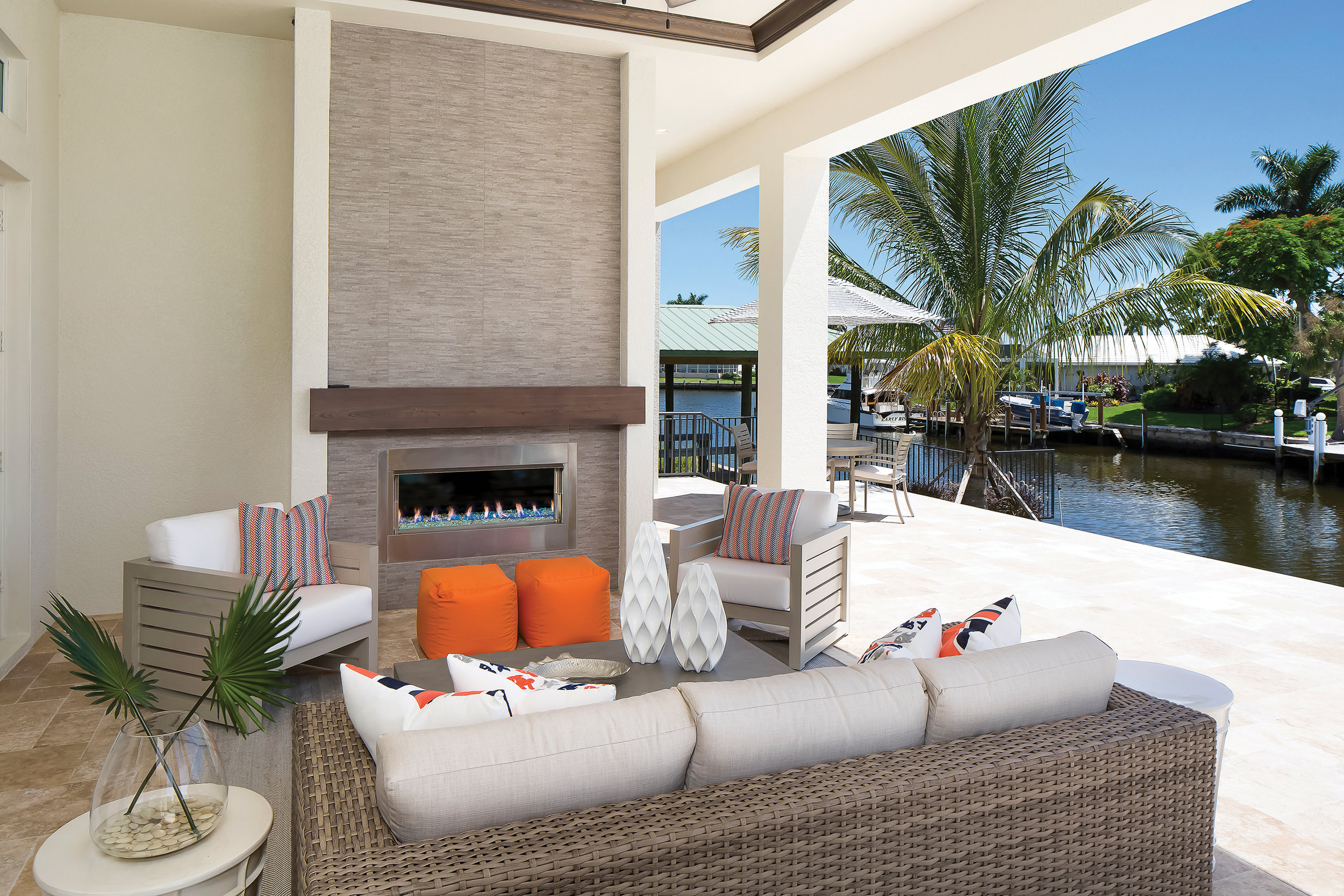  The lanai offers multiple seating and entertaining areas. The main living space is a fun mix of vibrant orange and resort-style seating options. The fireplace with vibrant blue glass and the feature wall create the perfect outdoor focal point. Beyon
