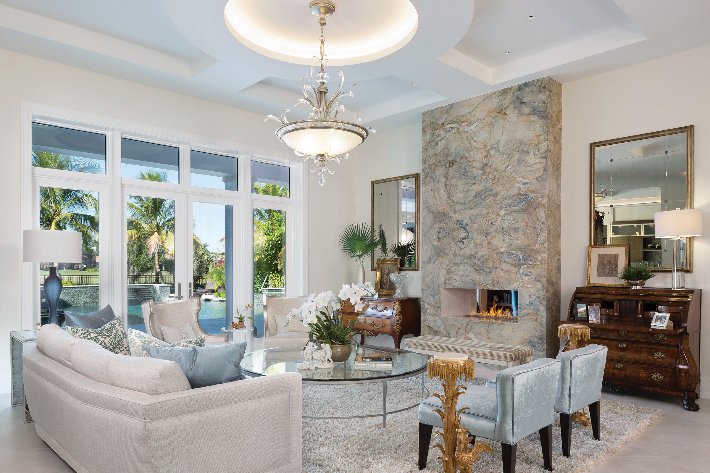  Inside, the formal living room is elegant and spacious thanks to the experts at Clive Daniel Home. Distinctive ceilings with floating LED accents and light wells provide a beautiful glow. The living room’s see-through Isokern fireplace with mitered 