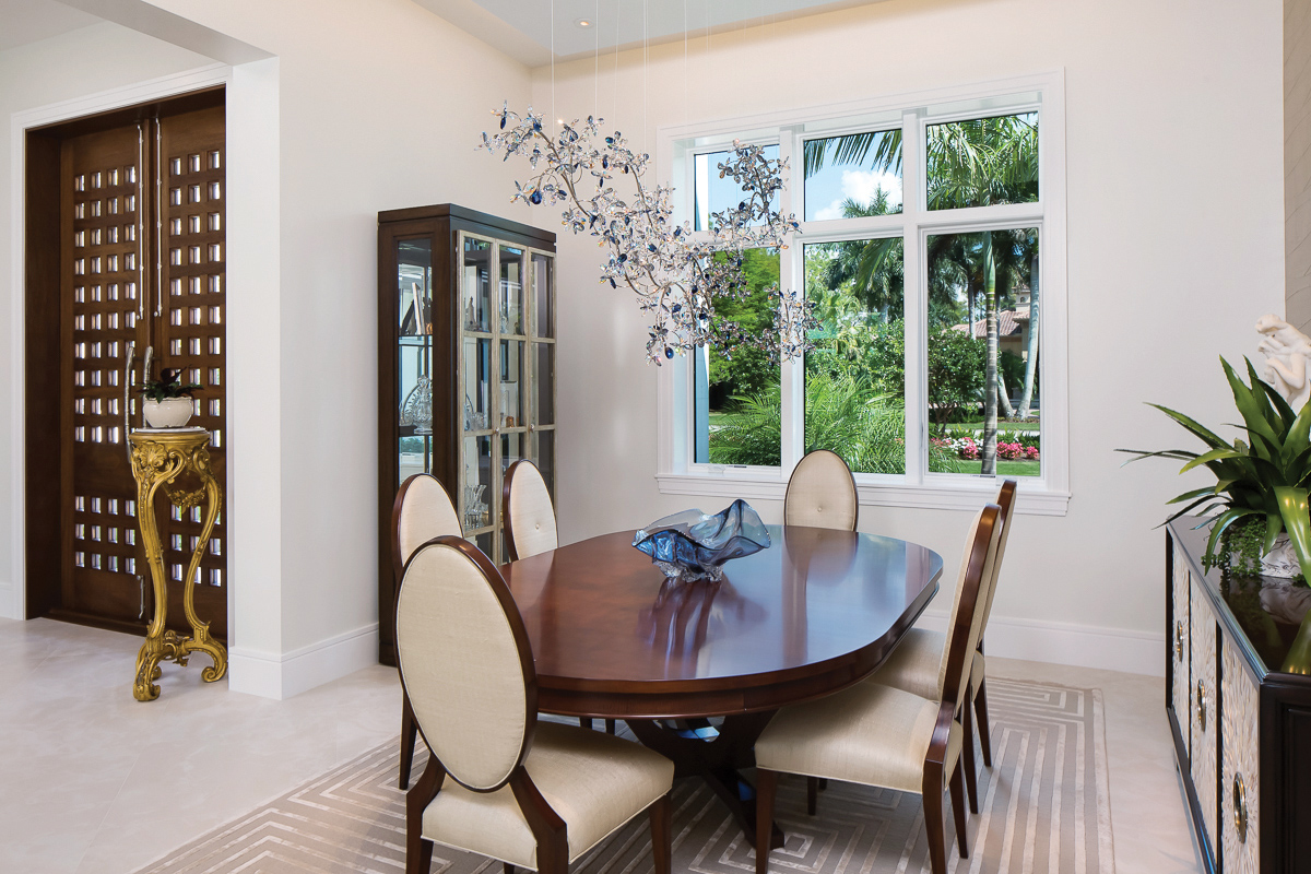  In the dining room, a unique Swarovski crystal light fixture casts playful reflections throughout the room. The adjacent wall features textured wallpaper for visual interest and the dark wood dining table comfortably seats six but can expand to acco