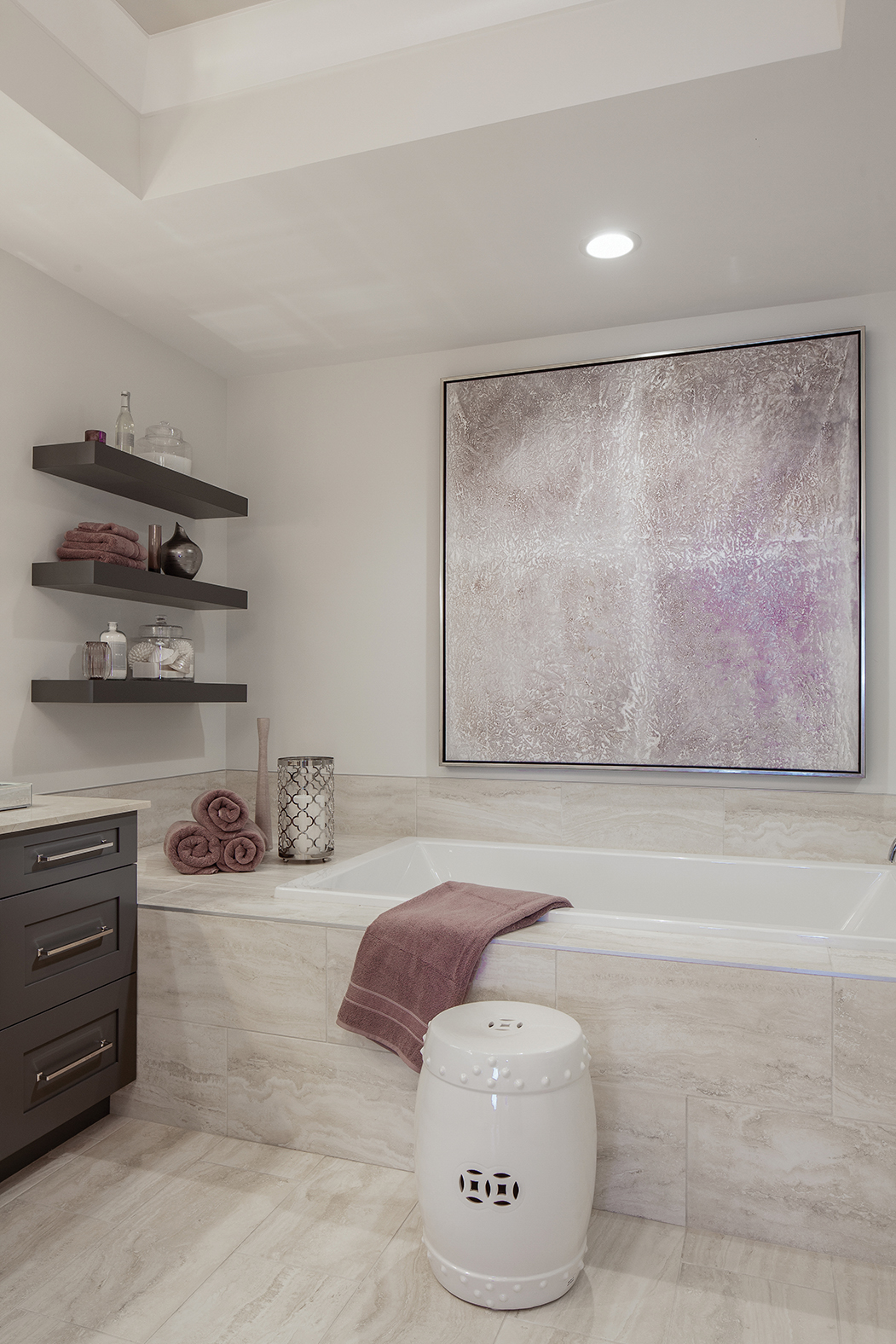  “Purple holds a great deal of sentimental value to the couple I worked with in this unit and they always weave it into their home no matter where they are located,” says Hall. Here, she used the color in a comfortable bathroom. Artwork over the tub 