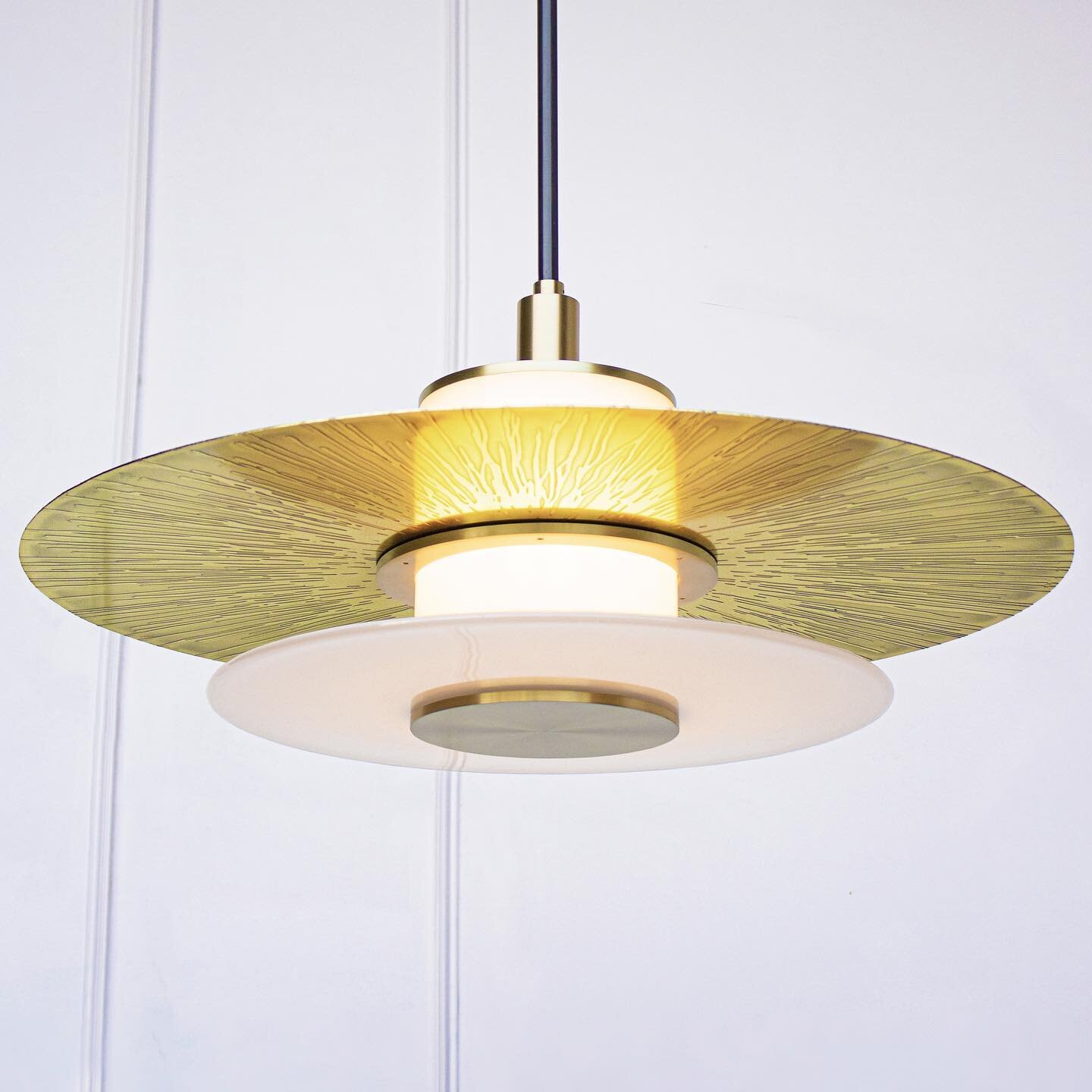 At 24 inches in diameter the Klein Pendant embraces a layered light assembly comprising a hand blown glass rondelle and an etched brass disc. Mounted to a central white light tube, the Klein Pendant offers ample up lighting as well as a soft and warm