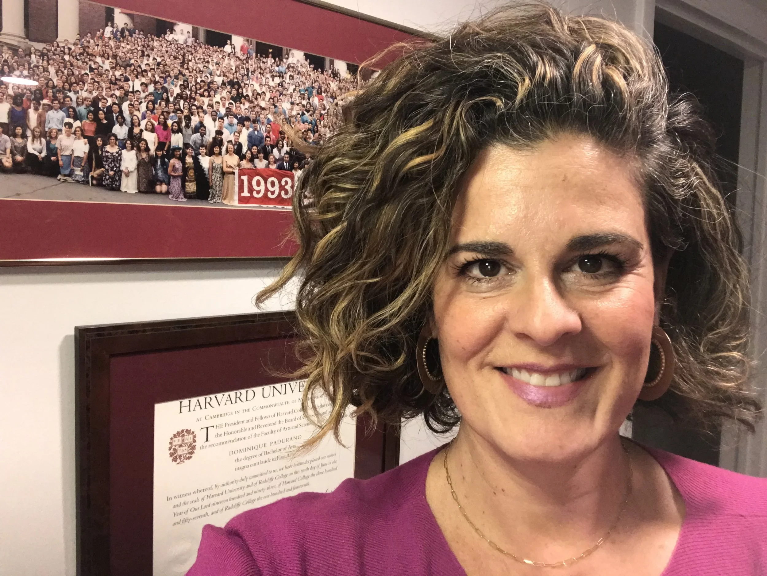 Dominique Padurano in front of her Harvard diploma and class photograph
