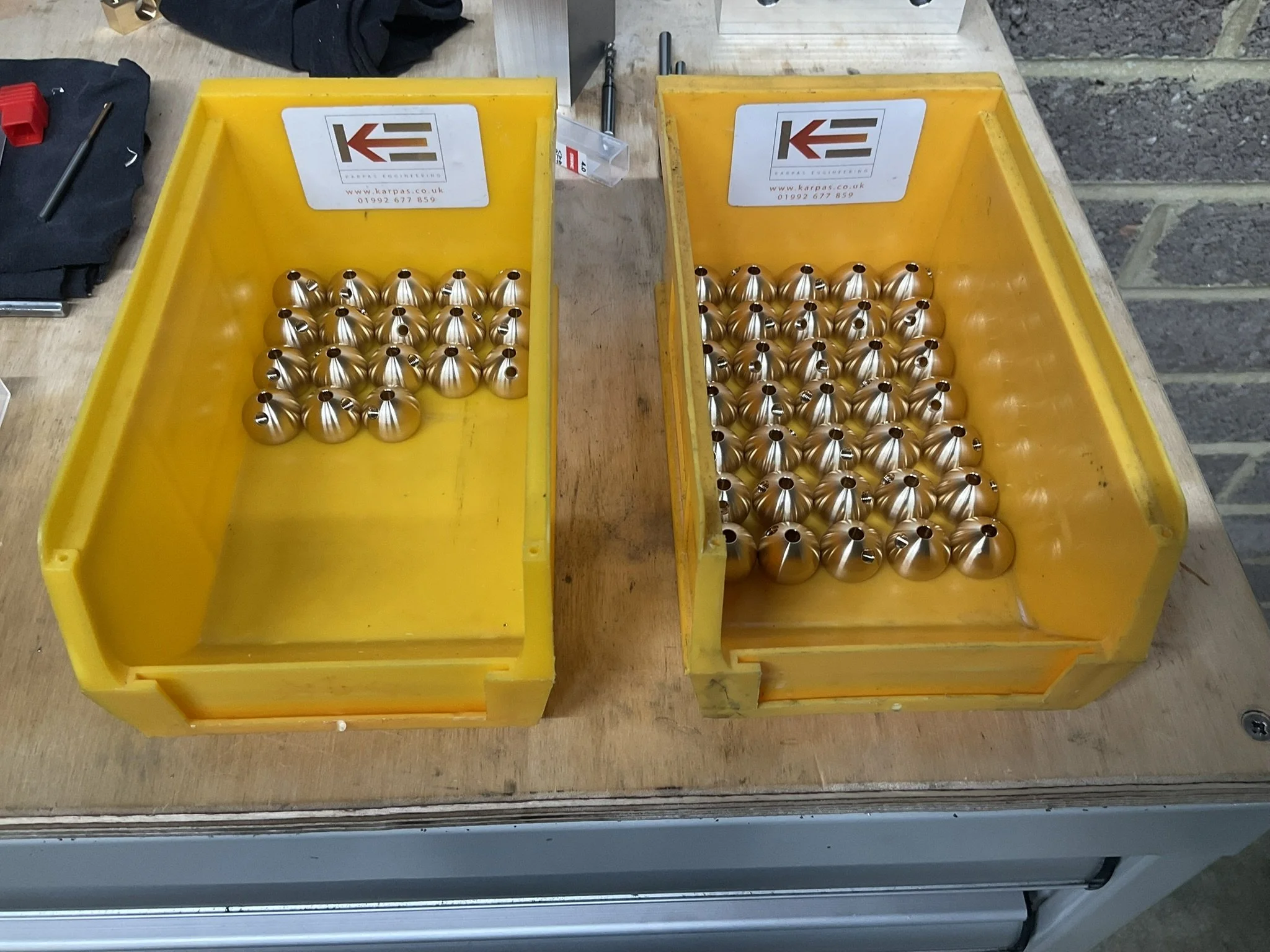 Small batch of CNC-turned brass components organised in a box after machining.