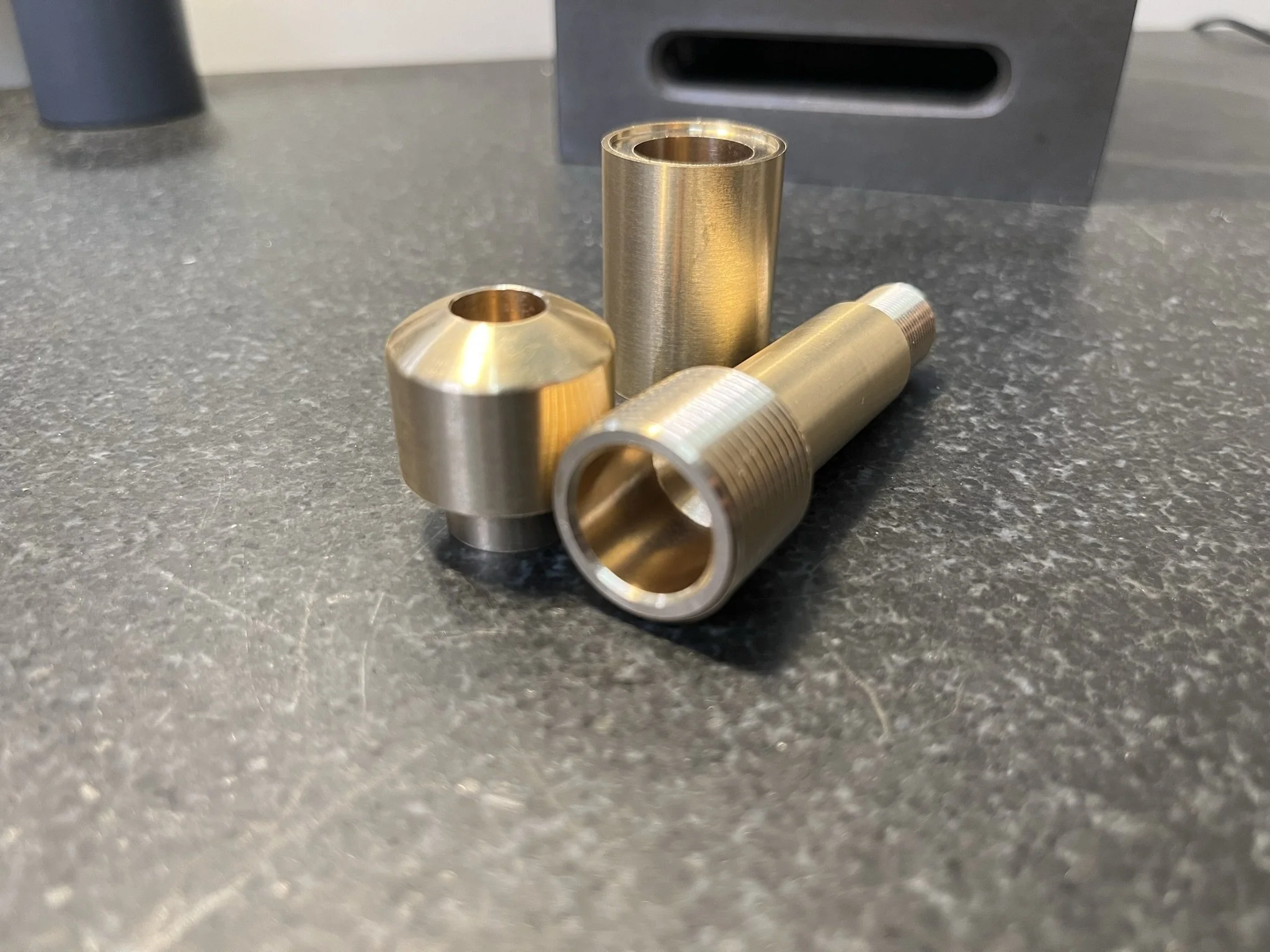 Batch of CNC turned brass components with threaded and precision features.