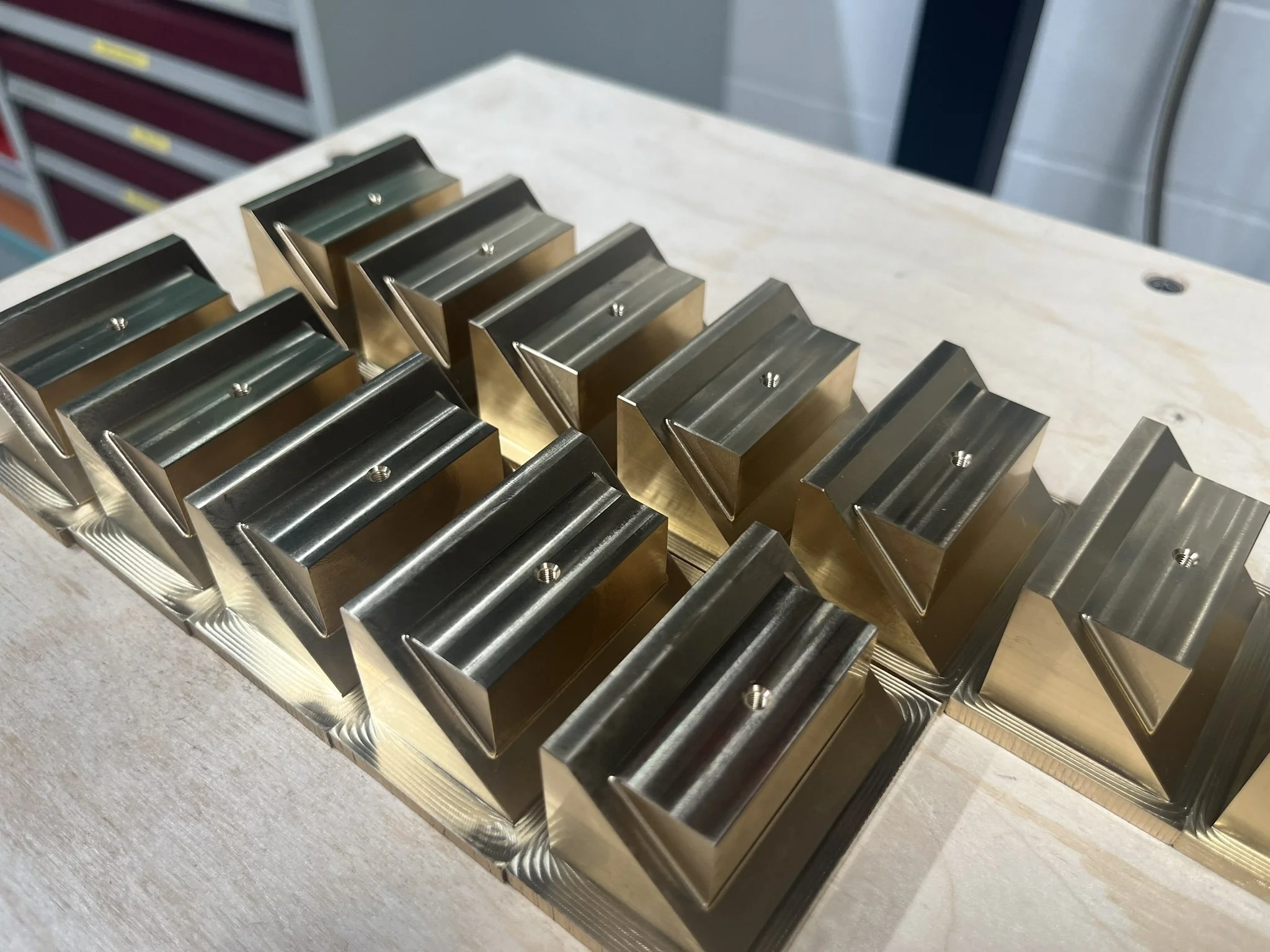First-operation CNC milling of brass blocks during small-batch production.