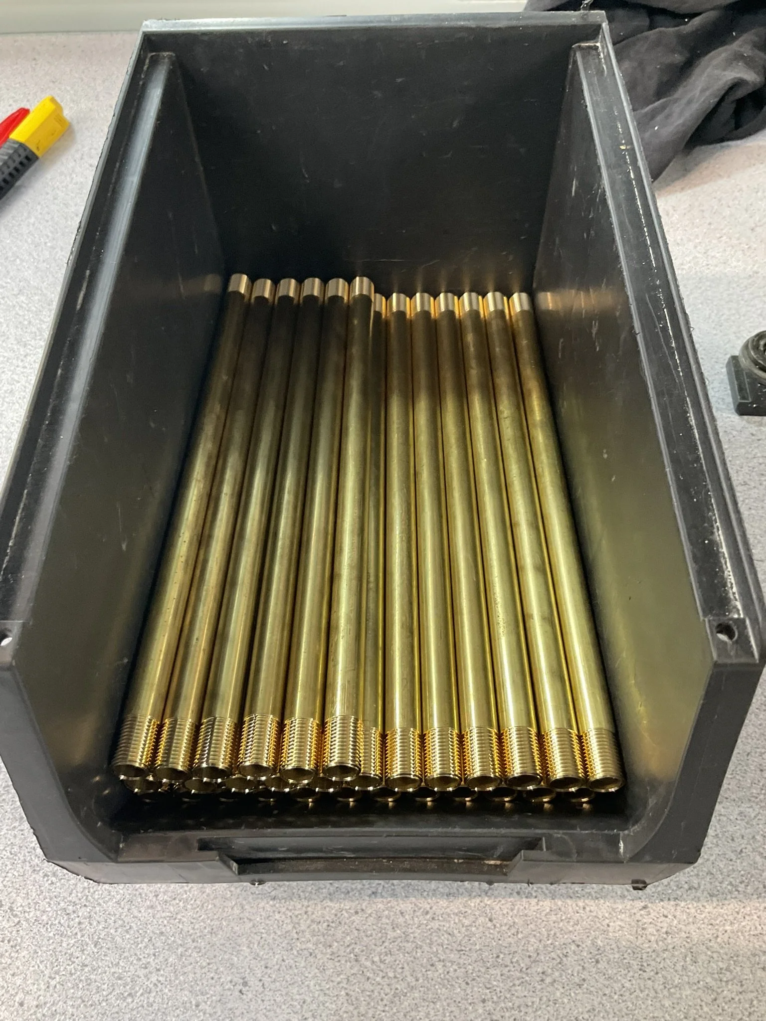 Batch of CNC-turned brass tubes with threaded ends.