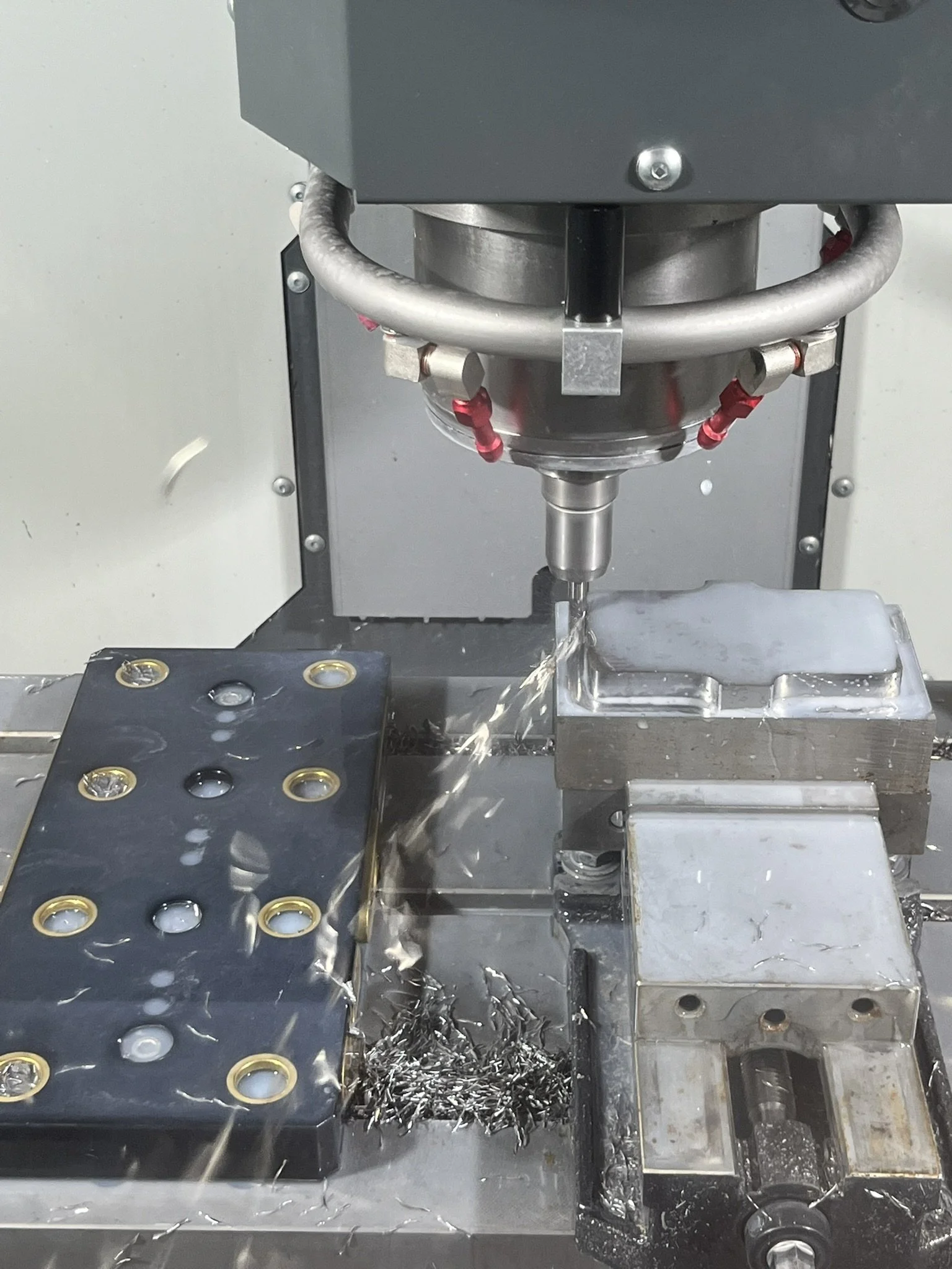 CNC milling aluminium component with coolant and chips during machining.