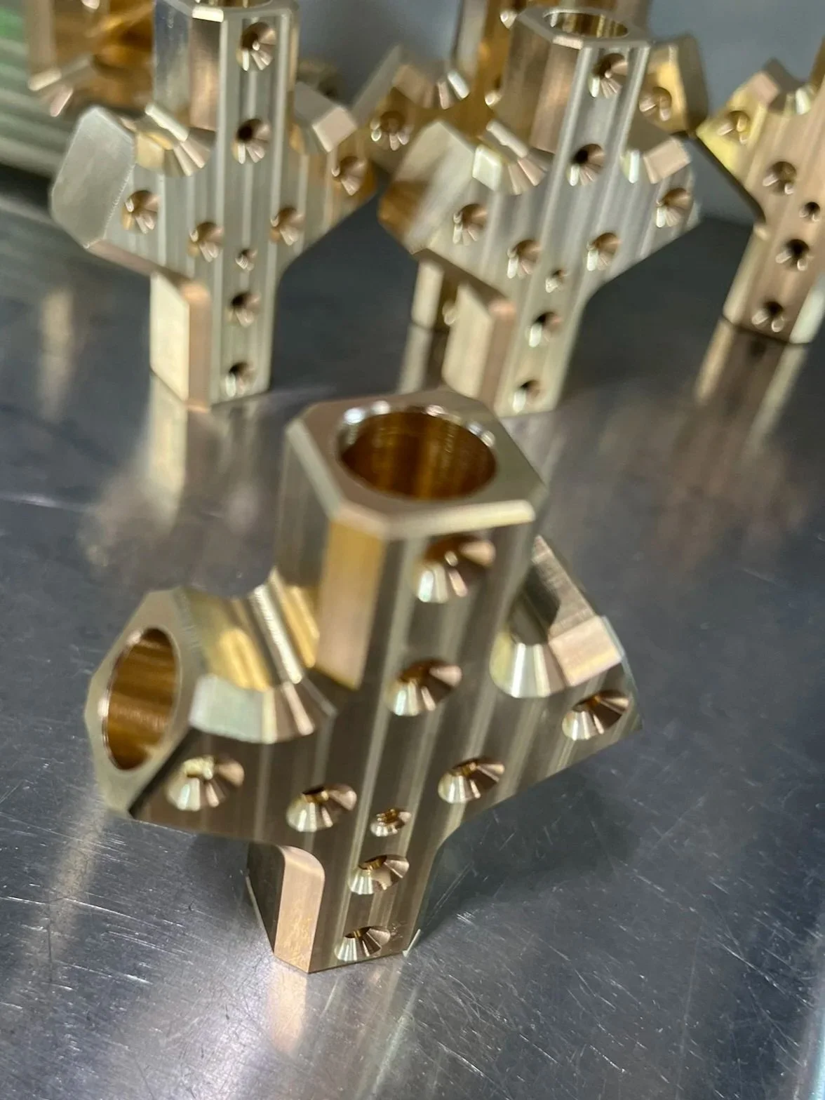 Batch of CNC machined brass lighting connectors with detailed threads and precision geometry.