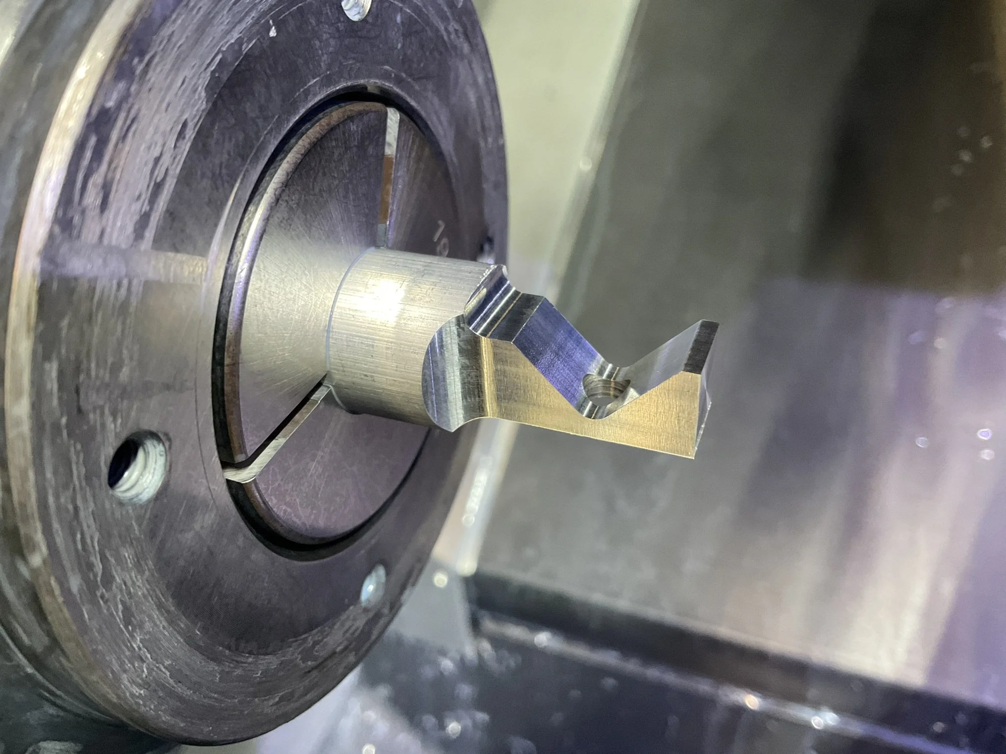 CNC-turned aluminium part in the lathe during machining.