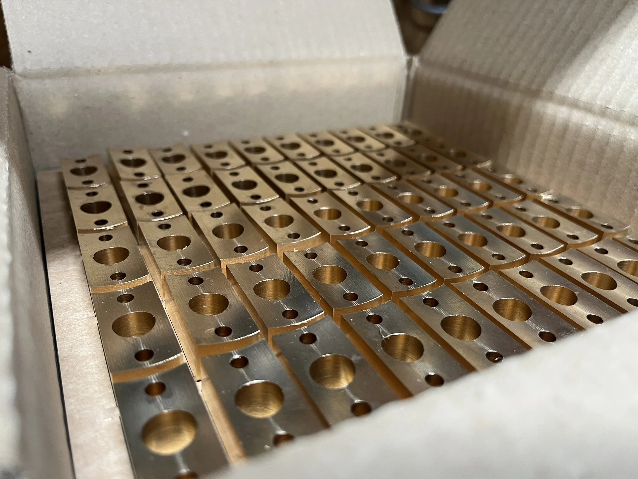 Batch of machined brass parts packed for sample build and pre-production testing.