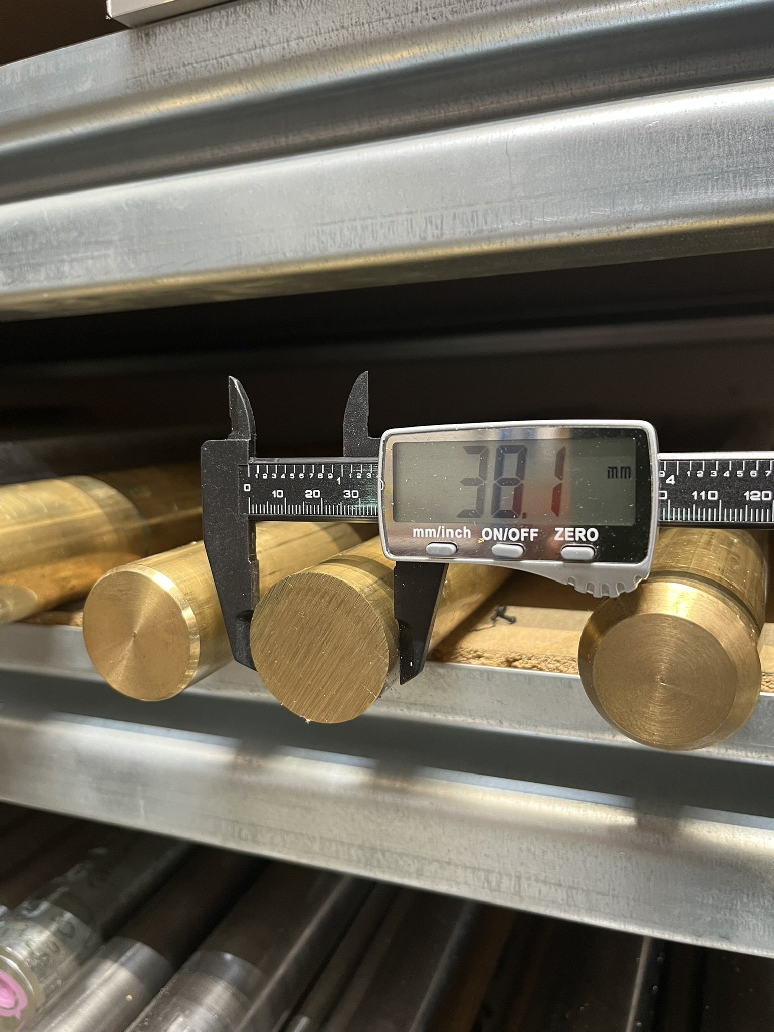 Brass bar stock being measured with digital calipers at Karpas Engineering workshop