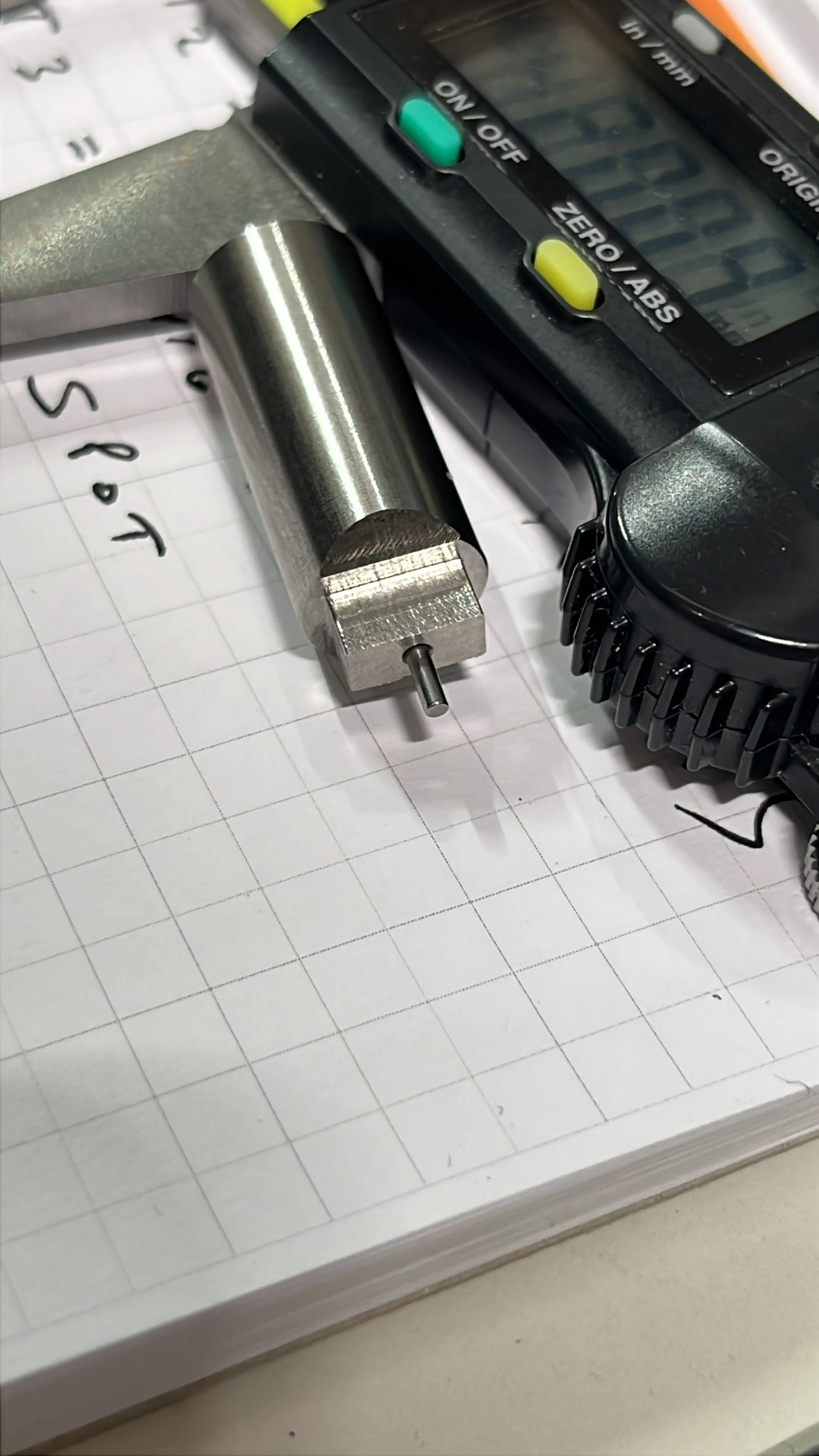 Complex CNC-turned component featuring a small tip end, shown alongside callipers during dimensional checking.