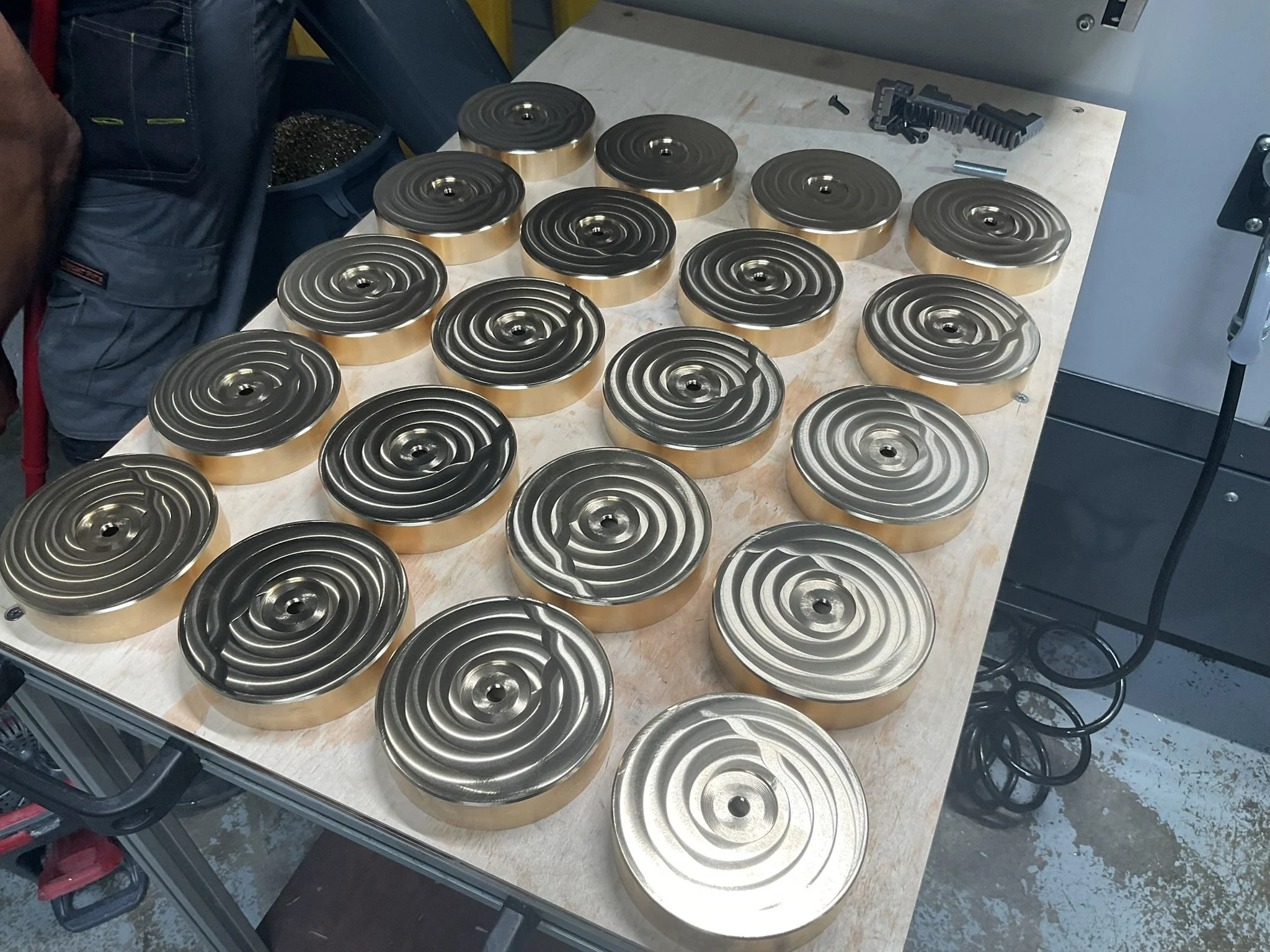 Batch of CNC machined brass lighting canopies for architectural lighting.