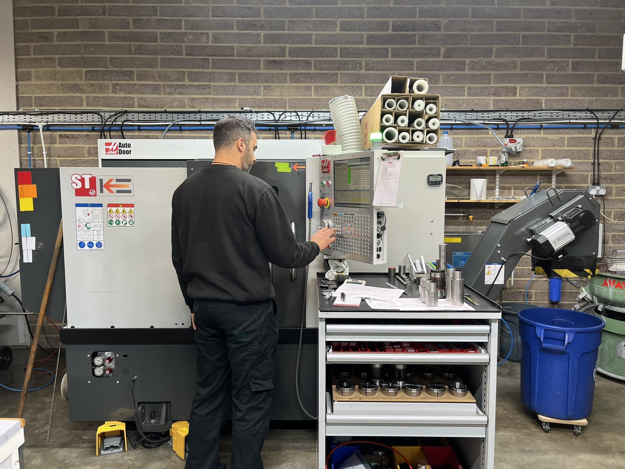 Engineer standing in front of a CNC lathe in the workshop.