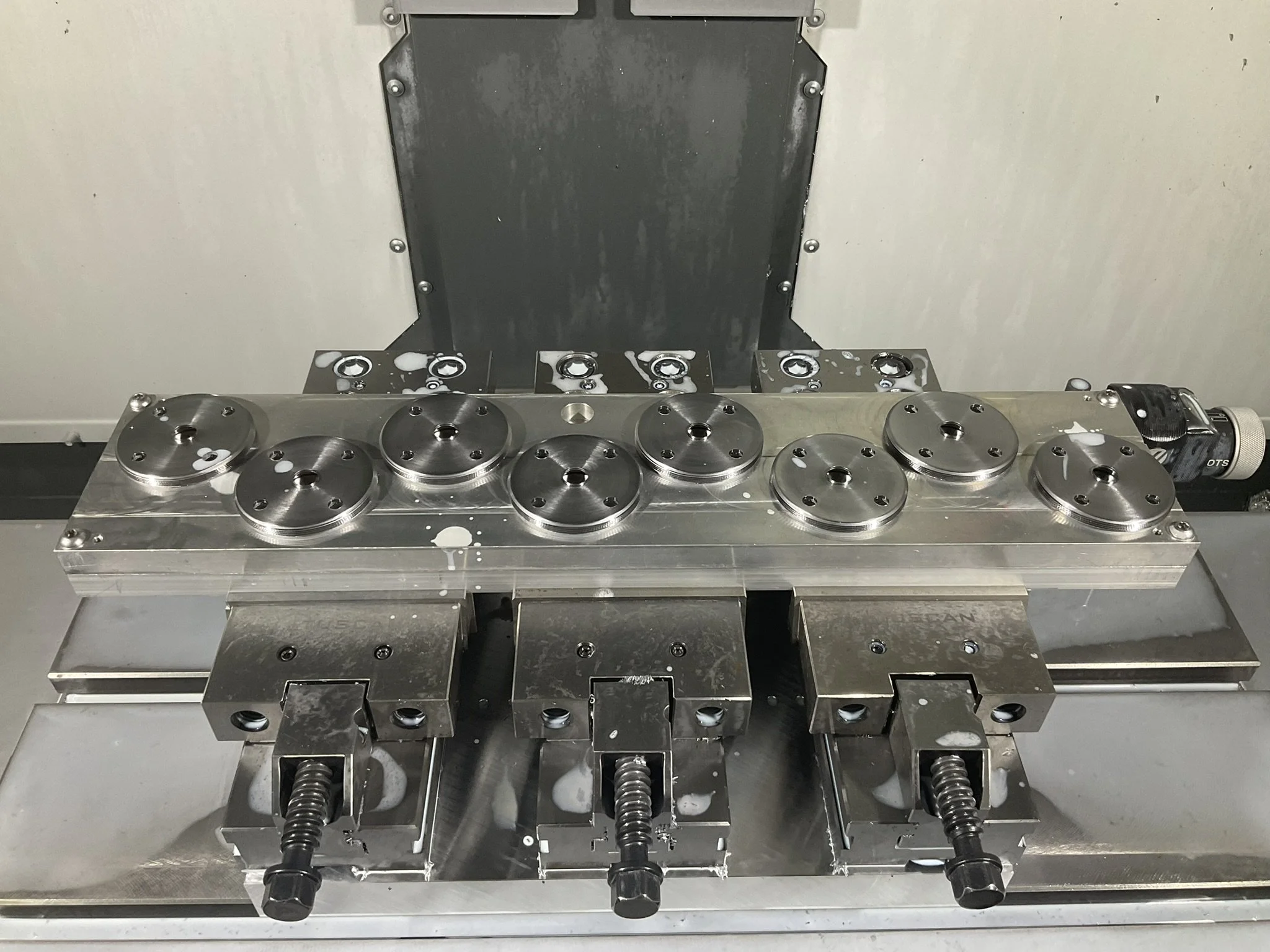 Large custom CNC-machined jig used to securely locate and machine multiple parts simultaneously during a milling operation.