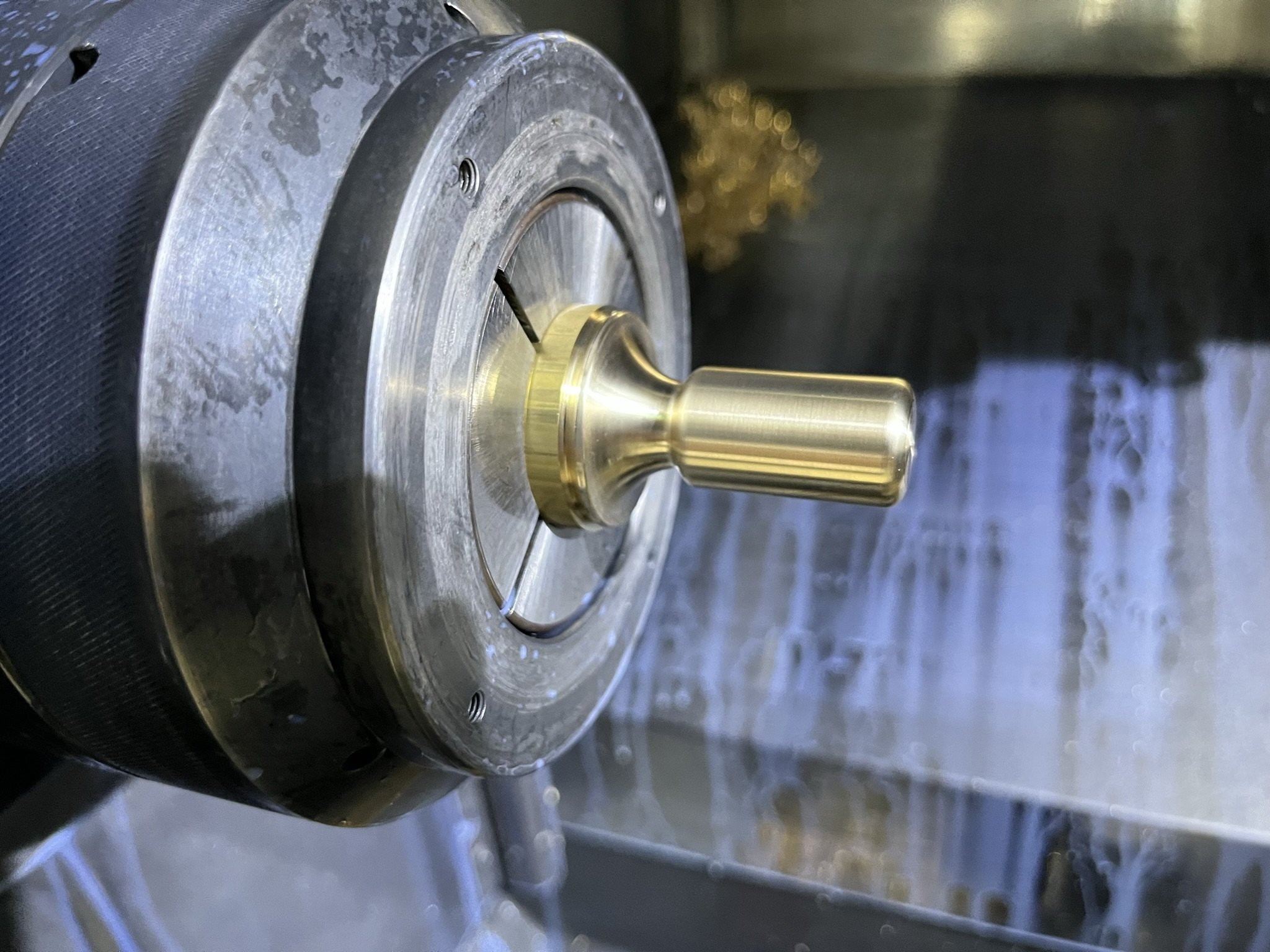 Brass lighting component being turned on a CNC lathe in our workshop