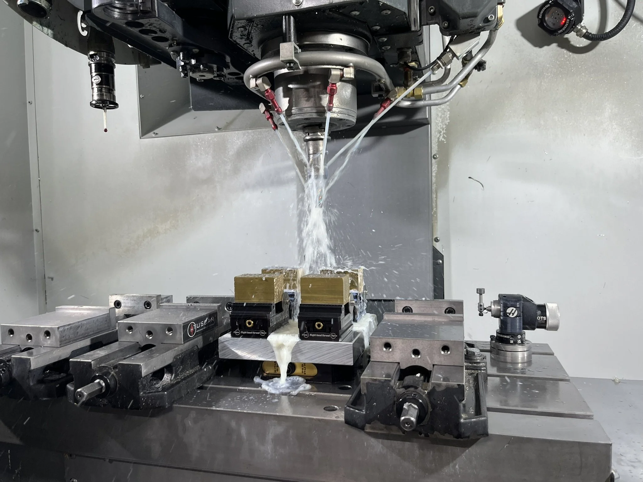 CNC milling a brass part held in vices.