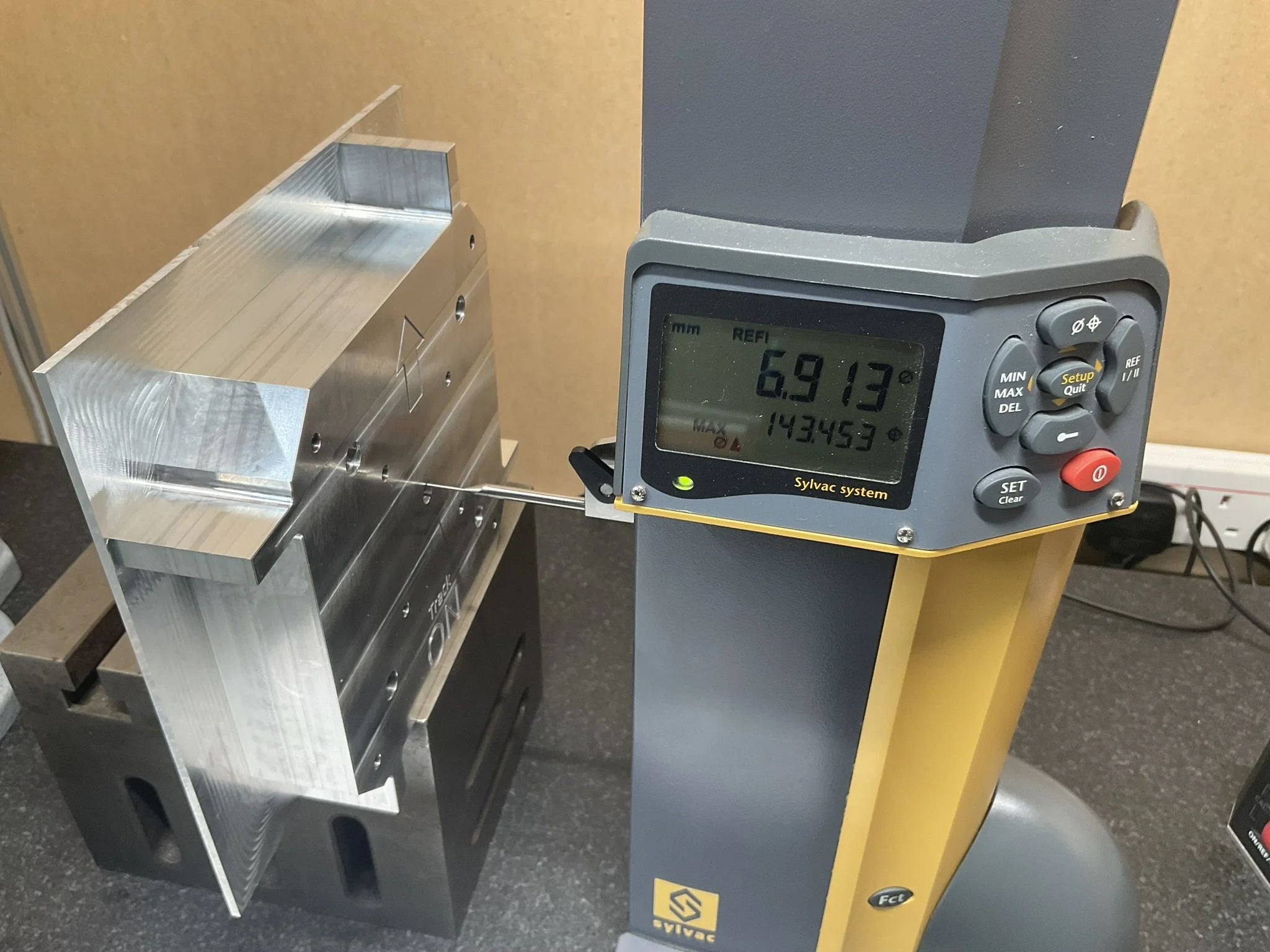 Quality control inspection measuring a complex machined part for accuracy.