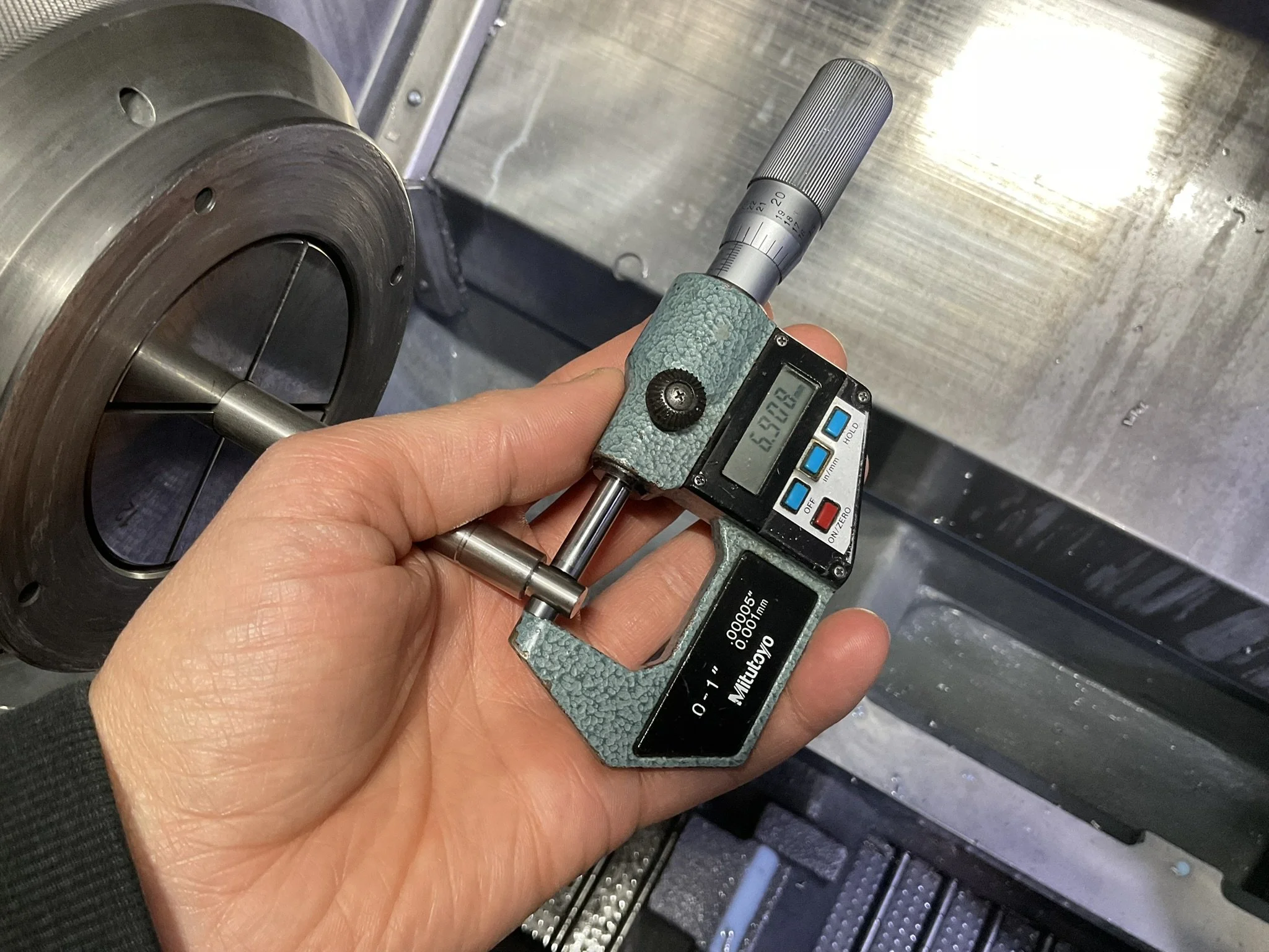 In-process measurement of a turned part using calipers on a CNC lathe