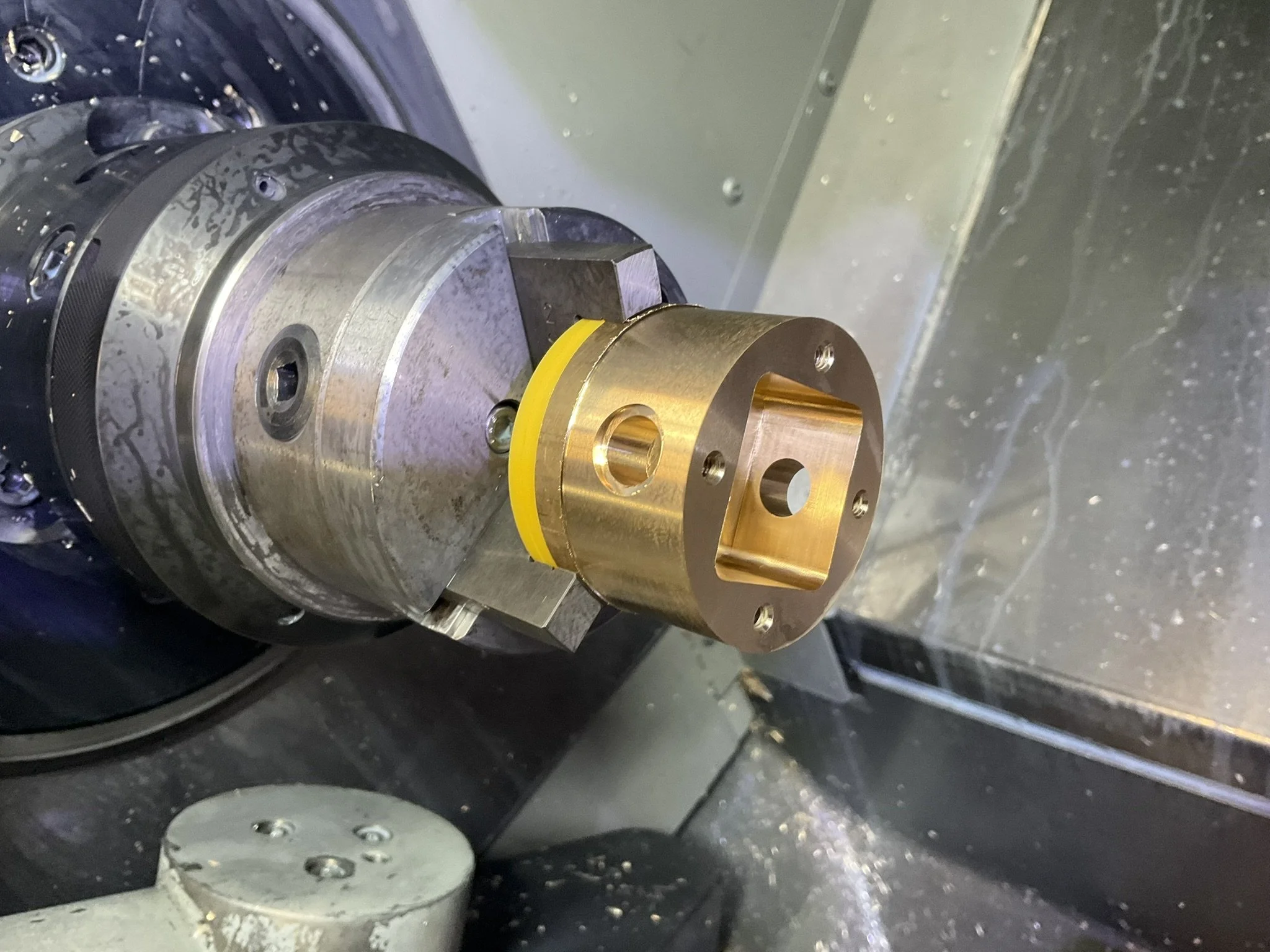 Complex brass part being machined on a CNC lathe.
