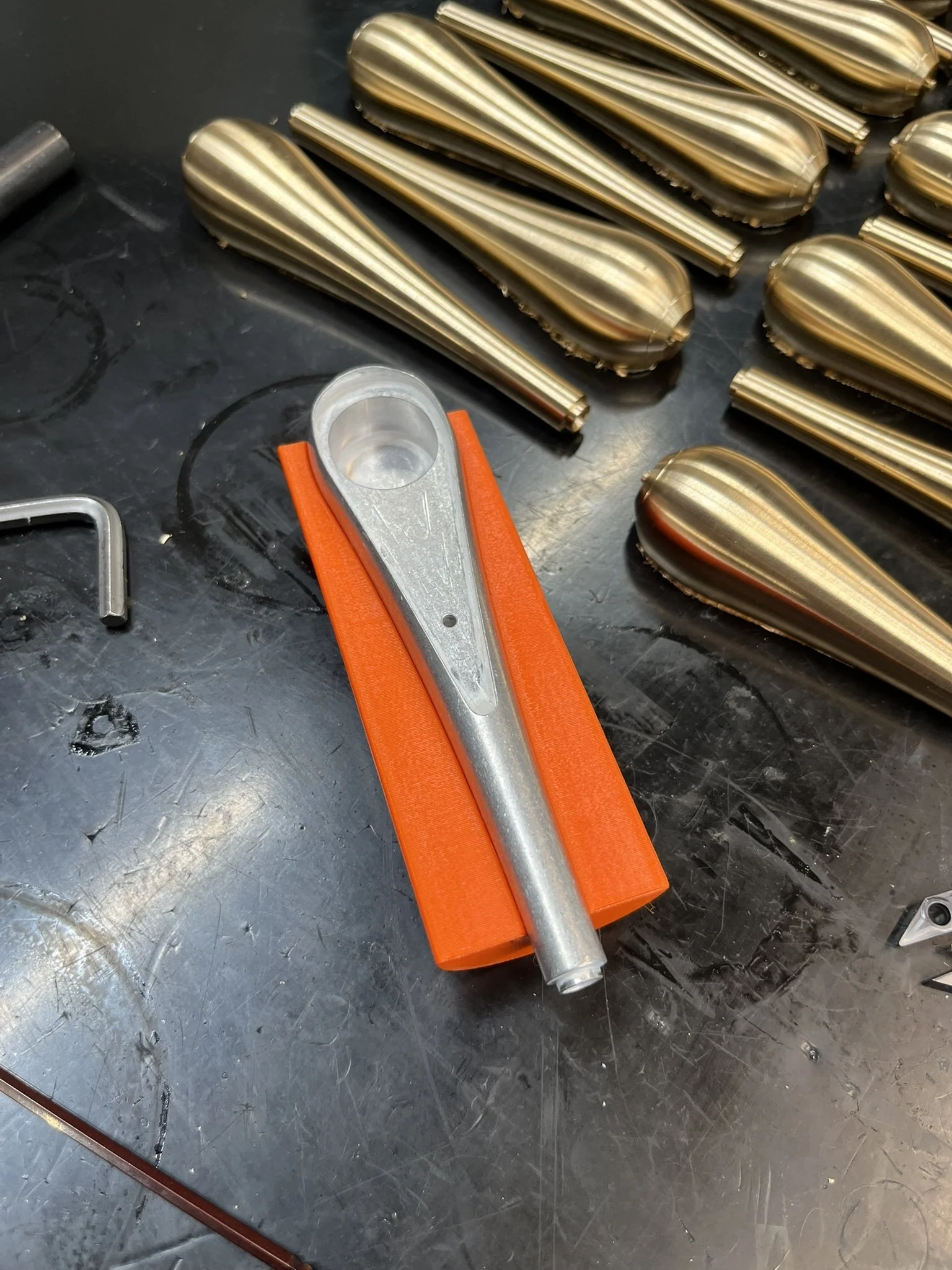 Custom 3D printed jig used to securely hold a complex pear-shaped brass component during CNC turning.