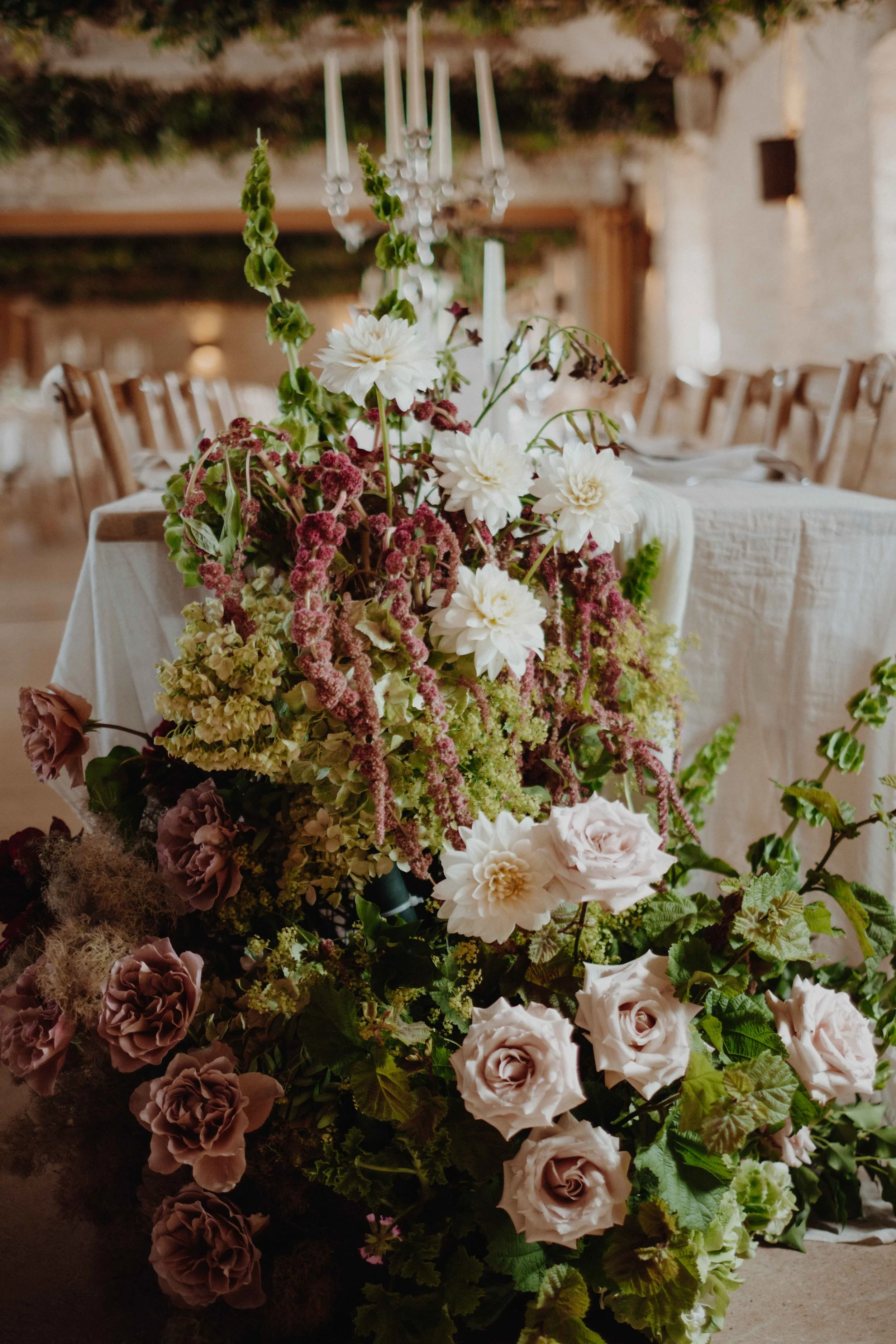 A floral centerpiece with white, pink, and mauve flowers on a dining table at an event.