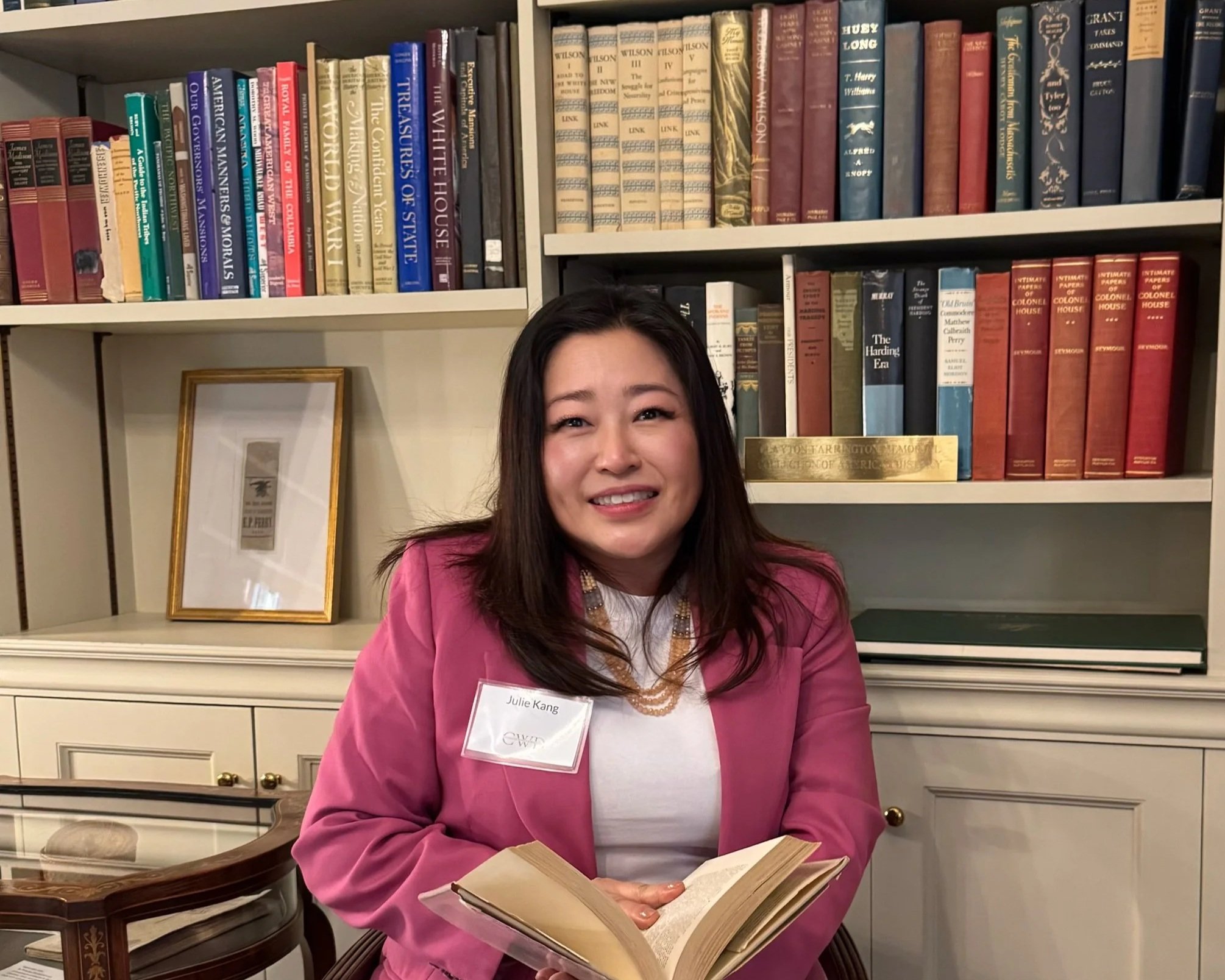 Julie Kang smiles at the camera while holding a book.