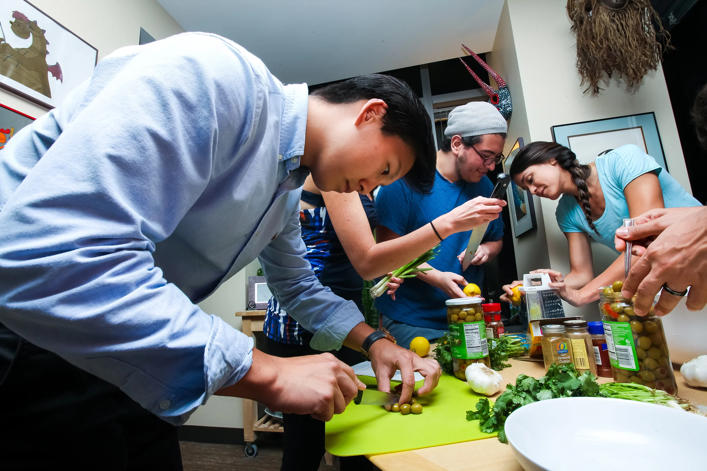 Shawn Cho (left), cuts olives during preparation of an eggplant and buckwheat dish called Chermoula. Behind him, Tamara Barboza (center) and Yashar Rahimpoov, grate lemon zest.
