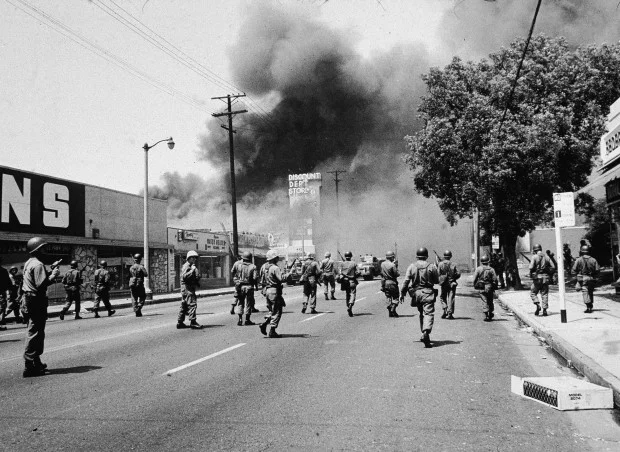Armed National Guardsmen march toward smoke on the horizon during the Watts riots in Los Angeles, California, August 1965. (Photo by Hulton Archive/Getty Images)