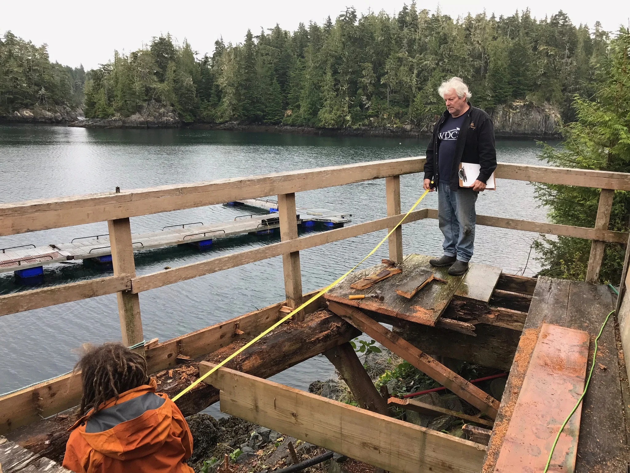 Mike Durban with clipboard, and Matchu Preville, working on the rotted out front deck of the lodge.