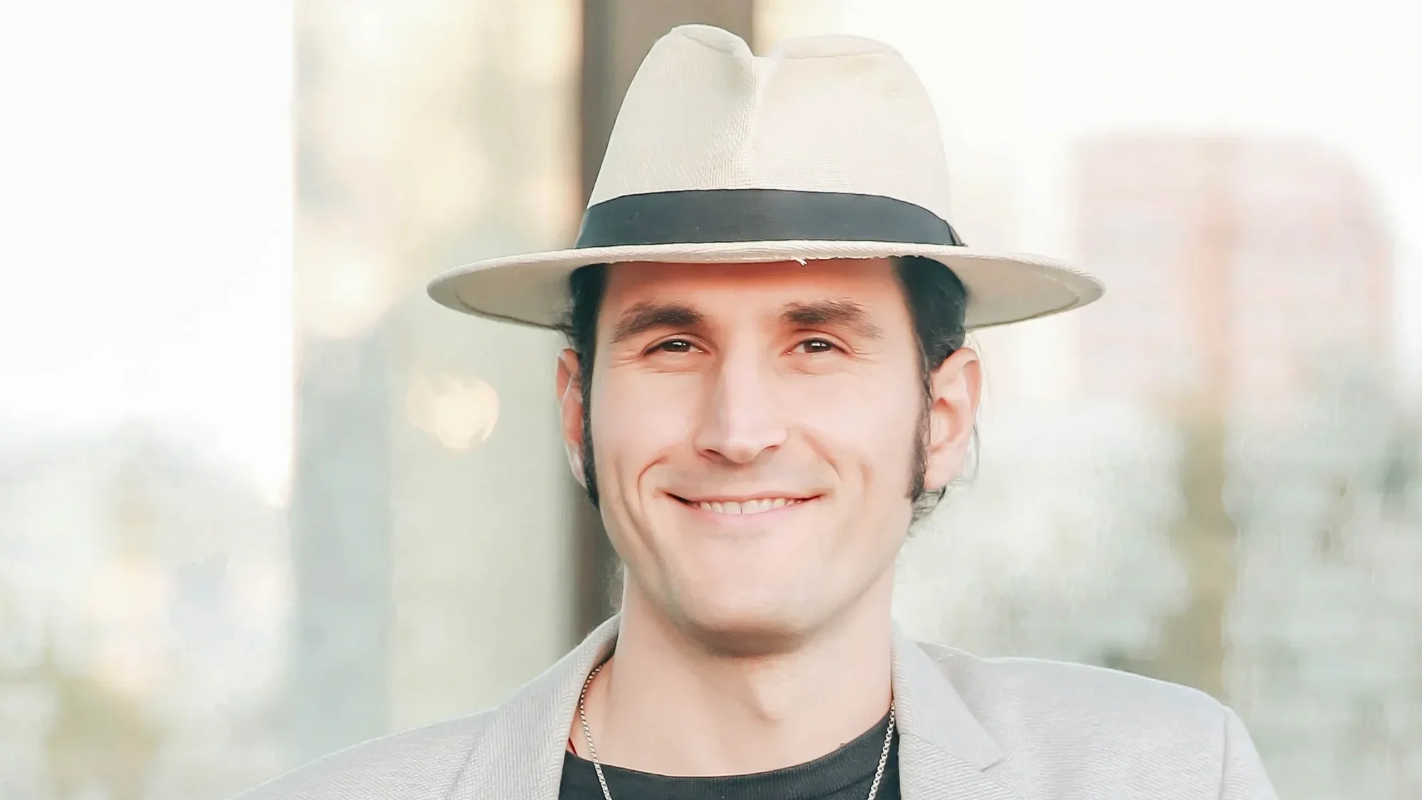Astrologer and spiritual teacher Nick Lasky smiling outdoors wearing a light-colored hat.
