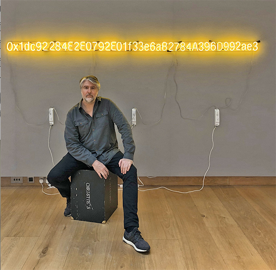 Kevin Abosch seatedin front of his artwork Yellow Lambo and I Am a Coin Series