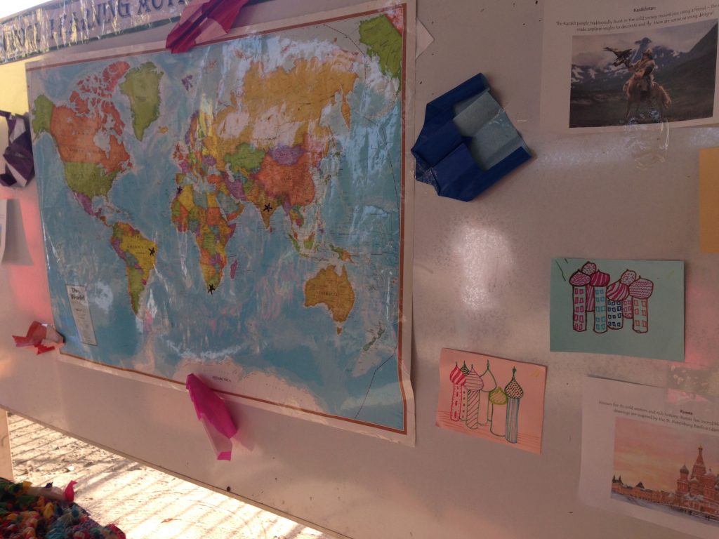 A map was the center of this board, filled with marks of the many places students traveled to this year. Around it, student art is displayed: St. Peter’s Basilica from Russia, and paper airplanes representing the companion hunting eagles from Kazakhstan.