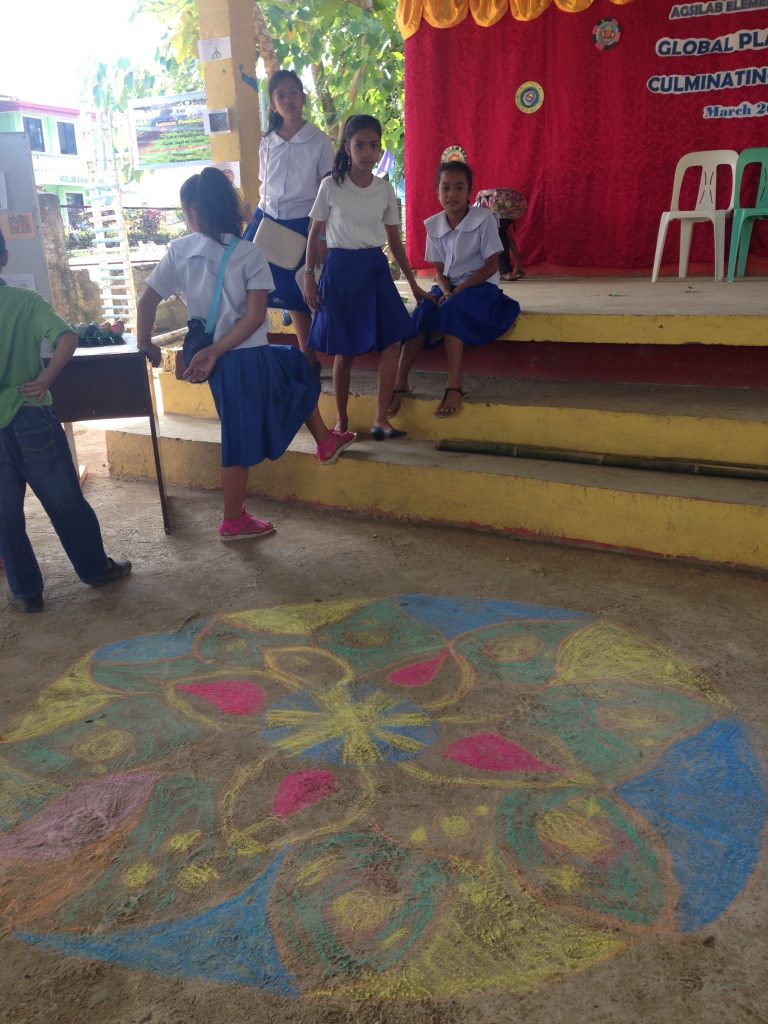 The older class spent time in India and Tibet, where they studied the ancient sacred mandala — a pattern that symbolizes the universe in Buddhism. After a unit on street art in Brazil, students took to heart the idea of spreading art wherever they go– seen in practice here, where several students chose to decorate the floors for the culminating event!