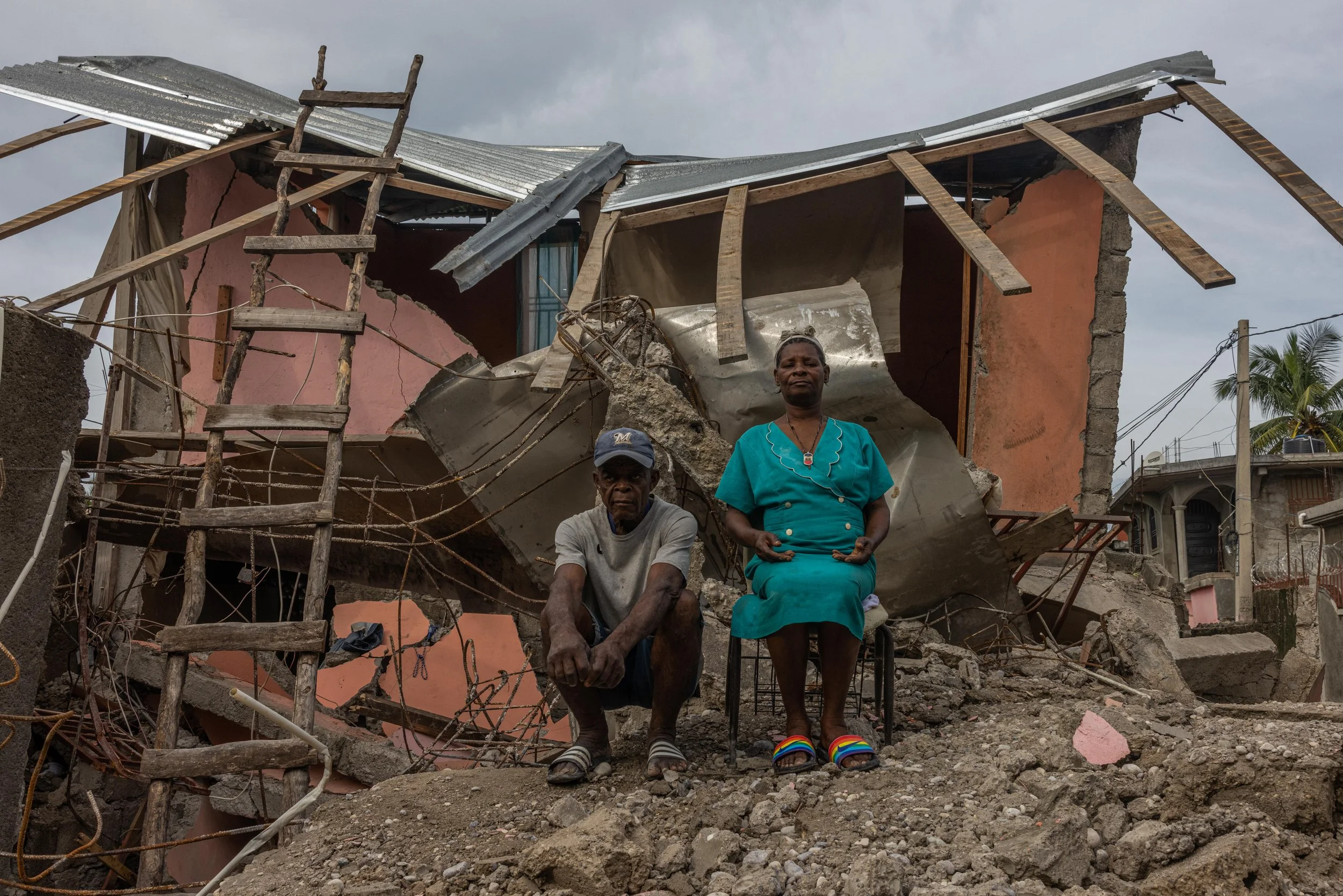  Marie-Anne and her neighbor sit in the rubble of her home following the earthquake in August 2021.  
