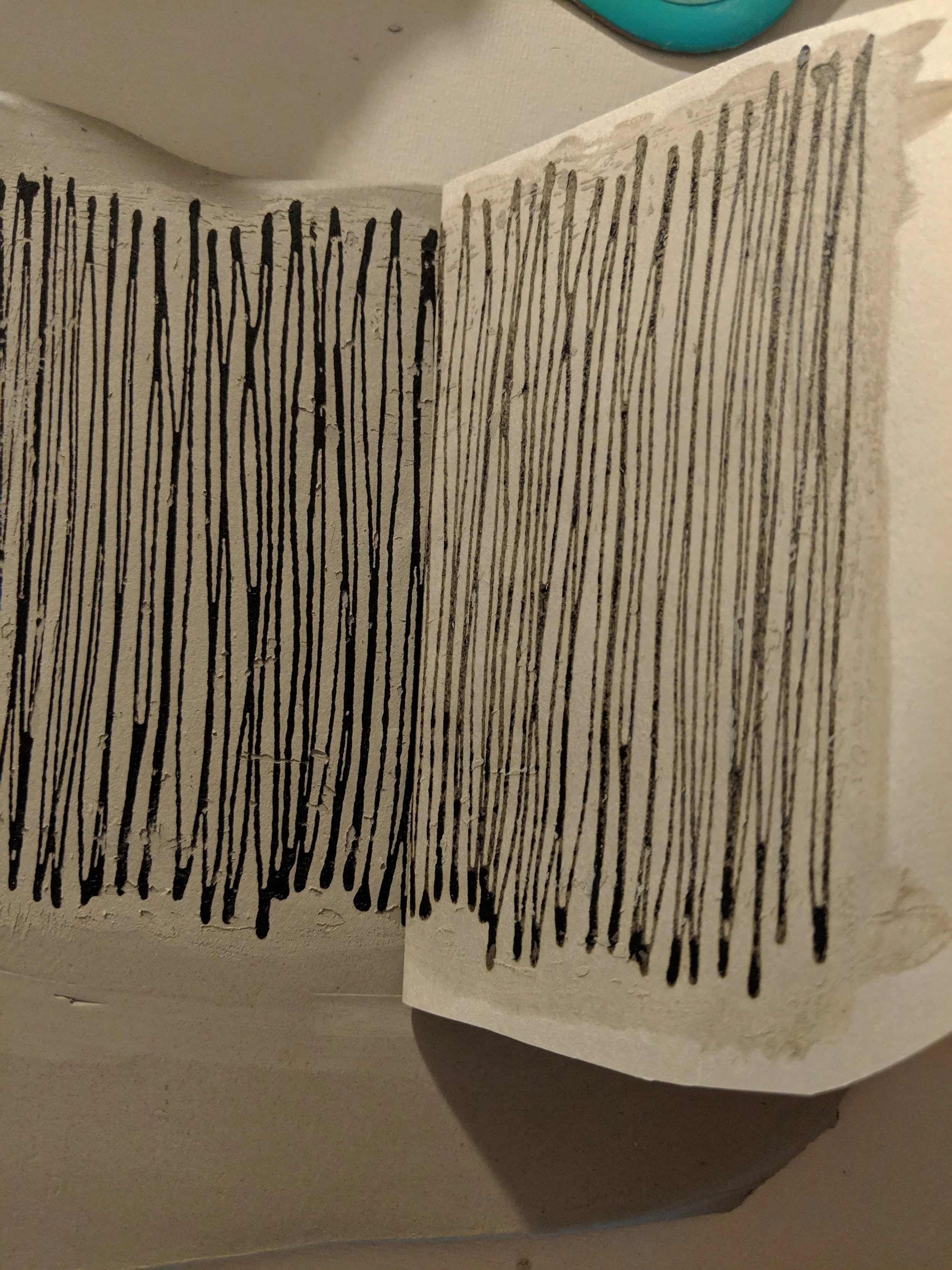 The newsprint being pulled up off the porcelain clay leaving the underglaze lines on the clay.