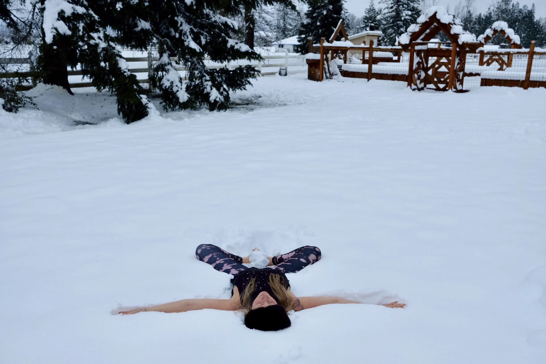 Brit playing in the snow and demonstrating reclined bound angle (supta baddha konasana) with her arms open and palms facing the sky— an excellent heart and hip opening posture.